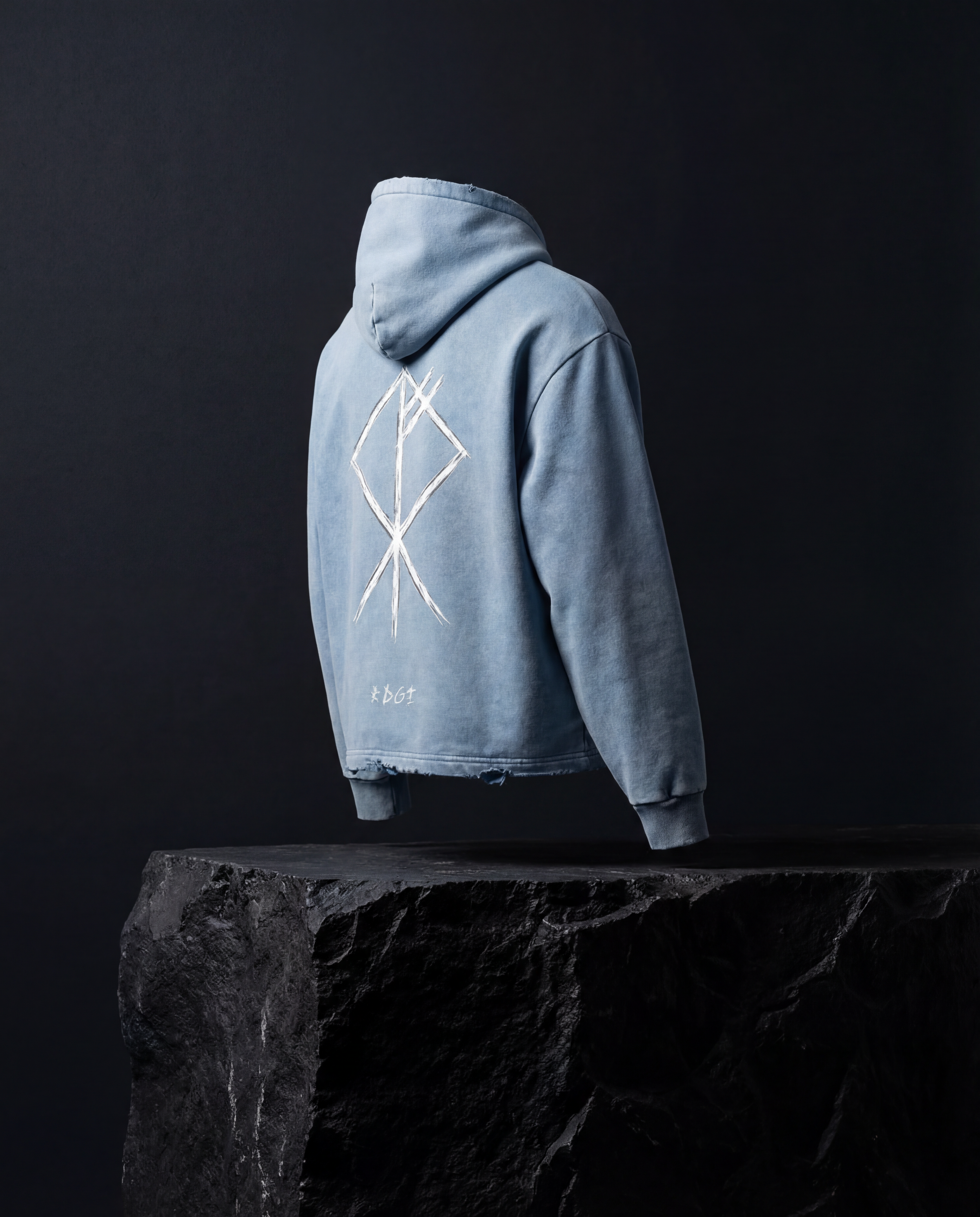 Light blue hoodie with a geometric design on the back, floating above a black textured surface against a dark background.