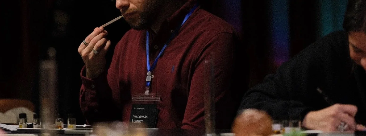 People at a table testing perfumes or scents with small vials, one person holding a scent strip.