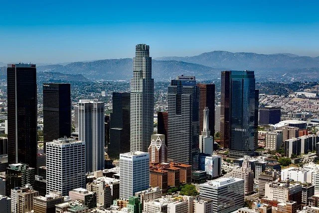 Skyscrapers and high-rise buildings in downtown Los Angeles with mountains in the background.