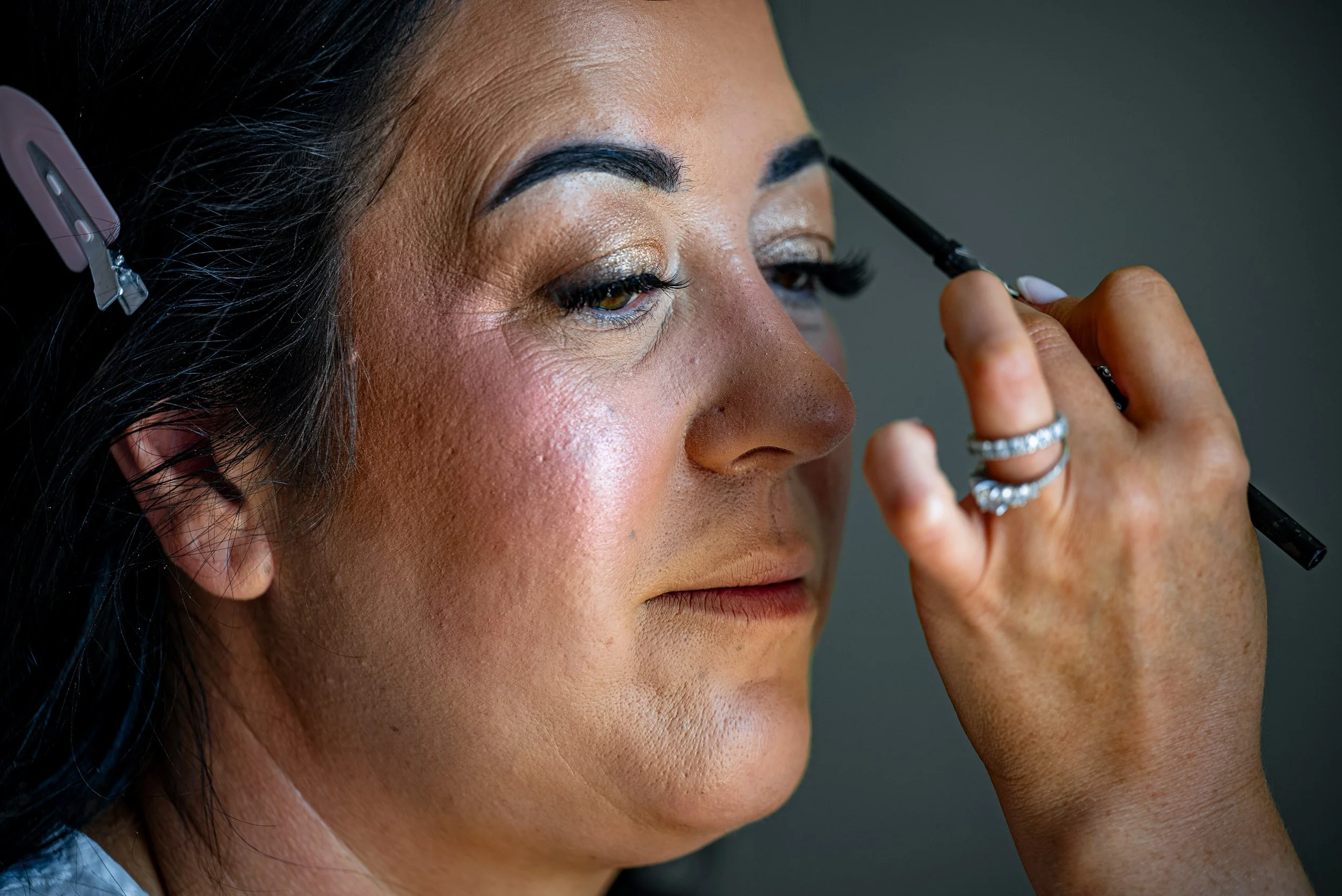 Close-up of a woman having makeup applied to her eyebrows with a brush, her face is being prepared or styled.