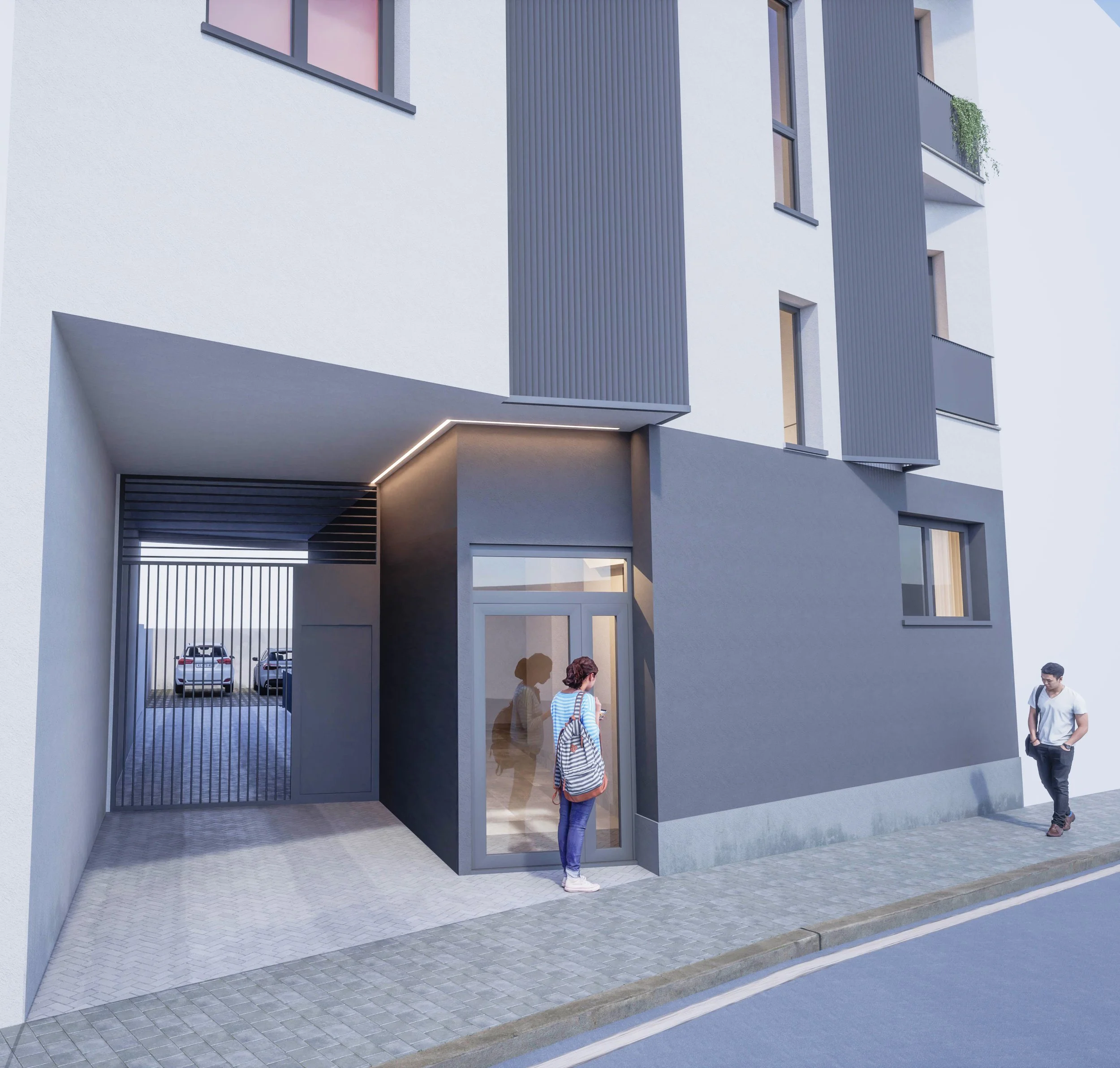Vista frontal de un edificio moderno con ventanas y balcones, entrada principal con una puerta de vidrio, y una zona de estacionamiento con reja. Dos personas, una mujer con mochila y un hombre, están en la acera.