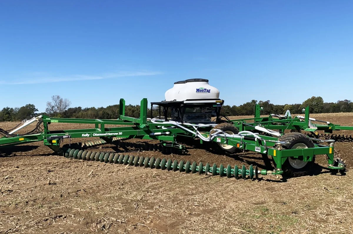 Montag Air Seeder on a KELLY Tillage Diamond Harrow 3009 in a field under a clear blue sky.