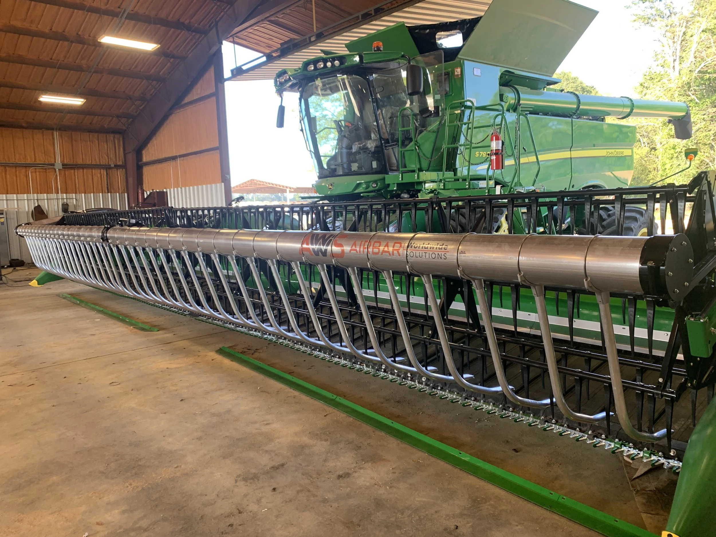 S3 AWS Airbar on a large green John Deere combine harvester inside a wooden storage shed.