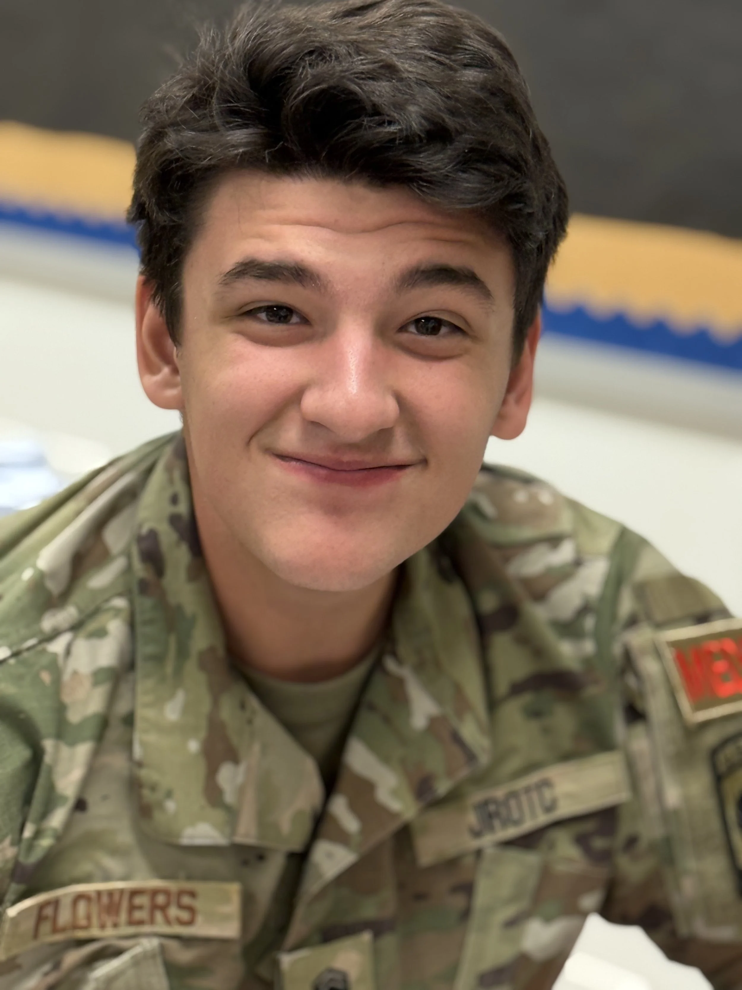 A young man in a military uniform smiling at the camera.