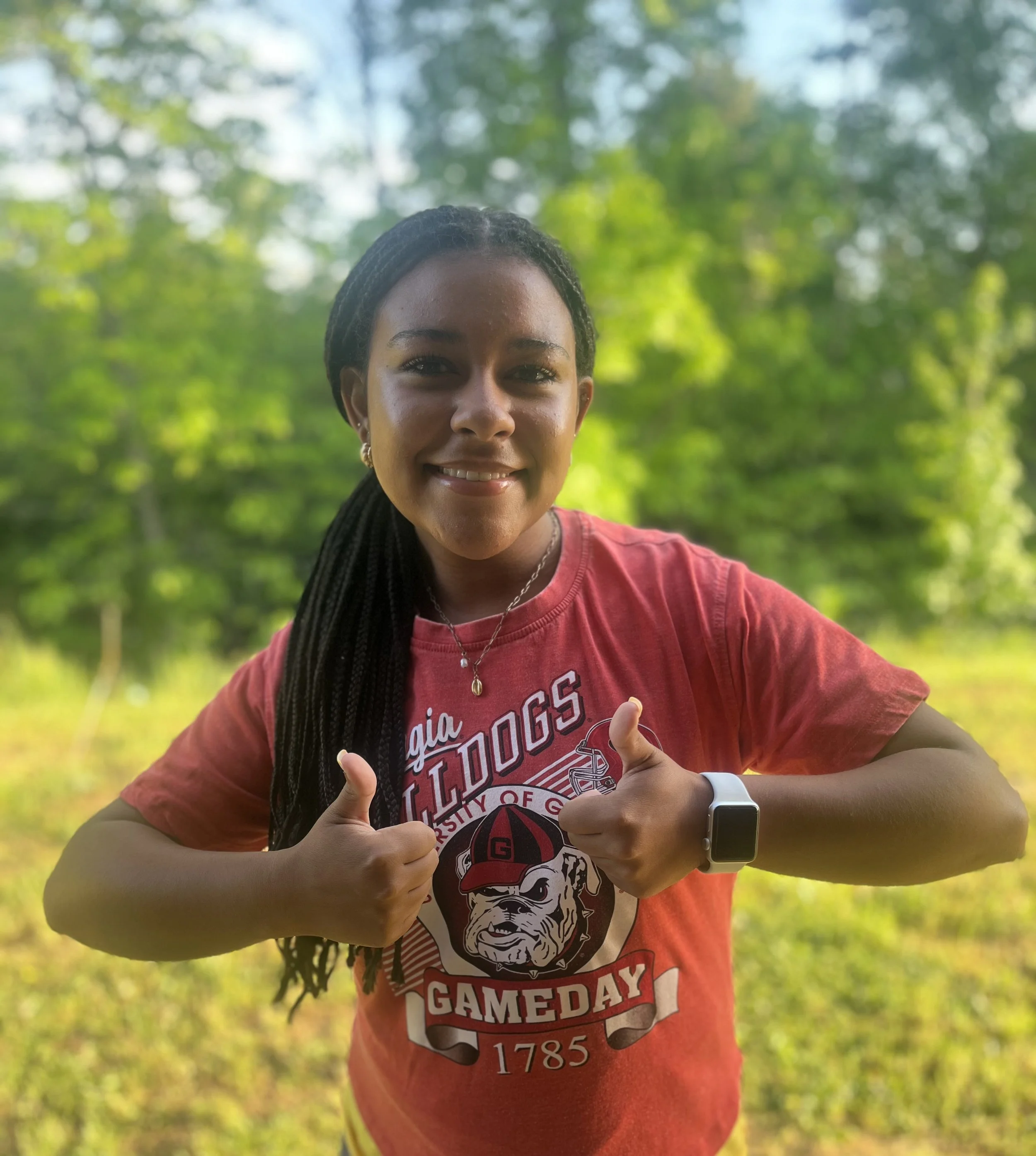 A smiling woman with long, curly hair sitting at a table with a water bottle in front of her.