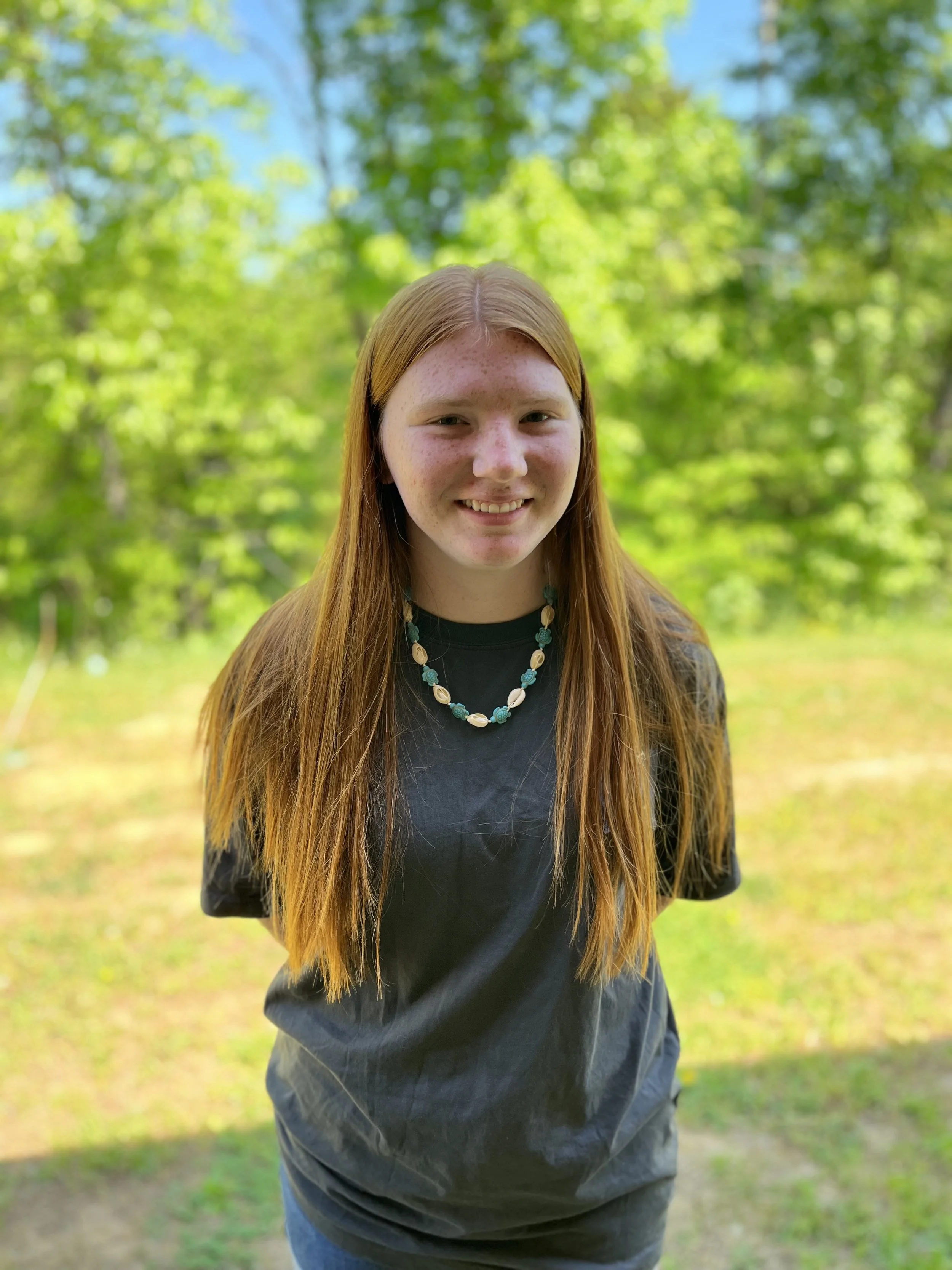 A young woman with red hair and freckles looking at the camera.