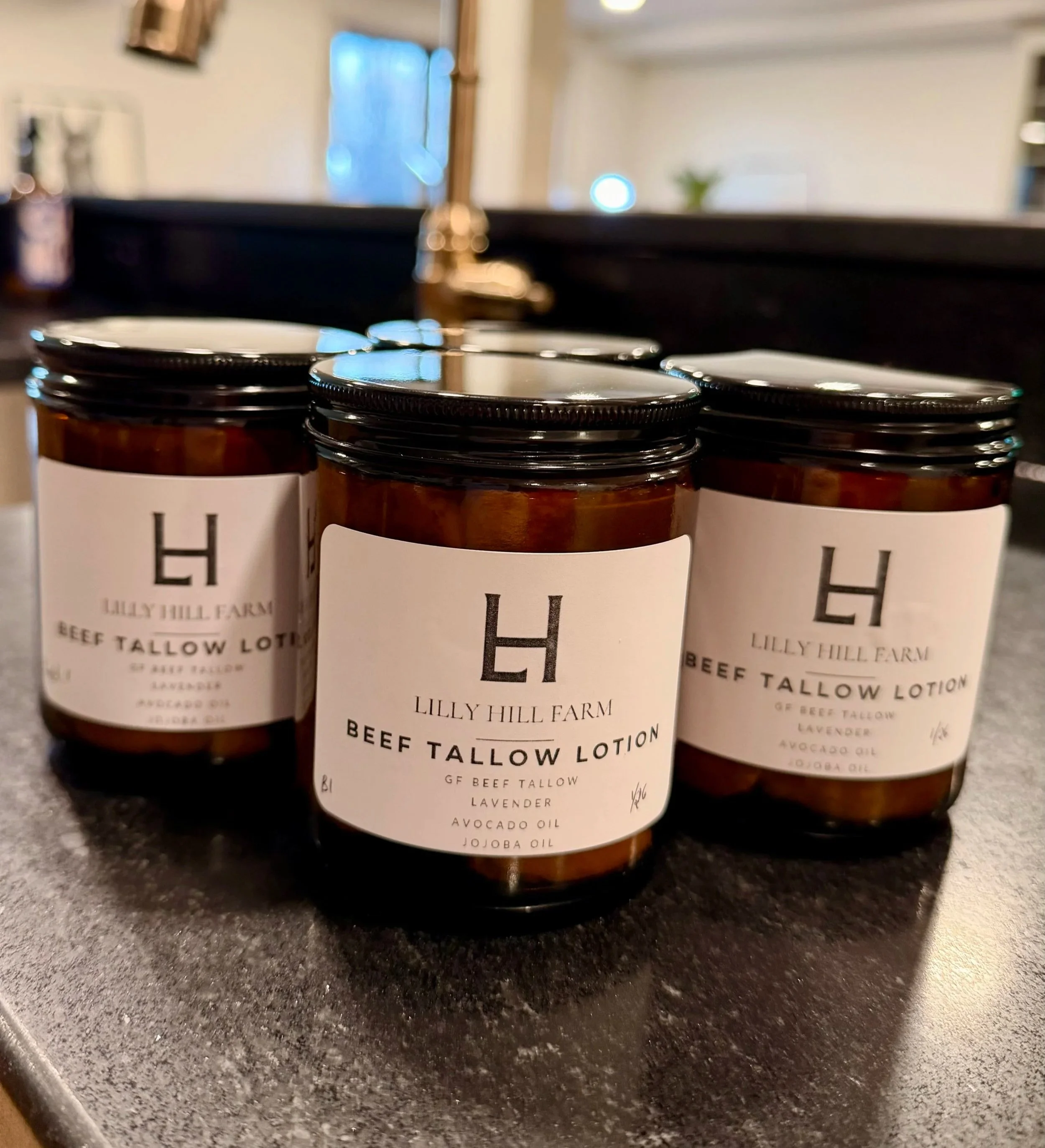 Three jars of Lilly Hill Farm Beef Tallow Lotion on a kitchen counter.