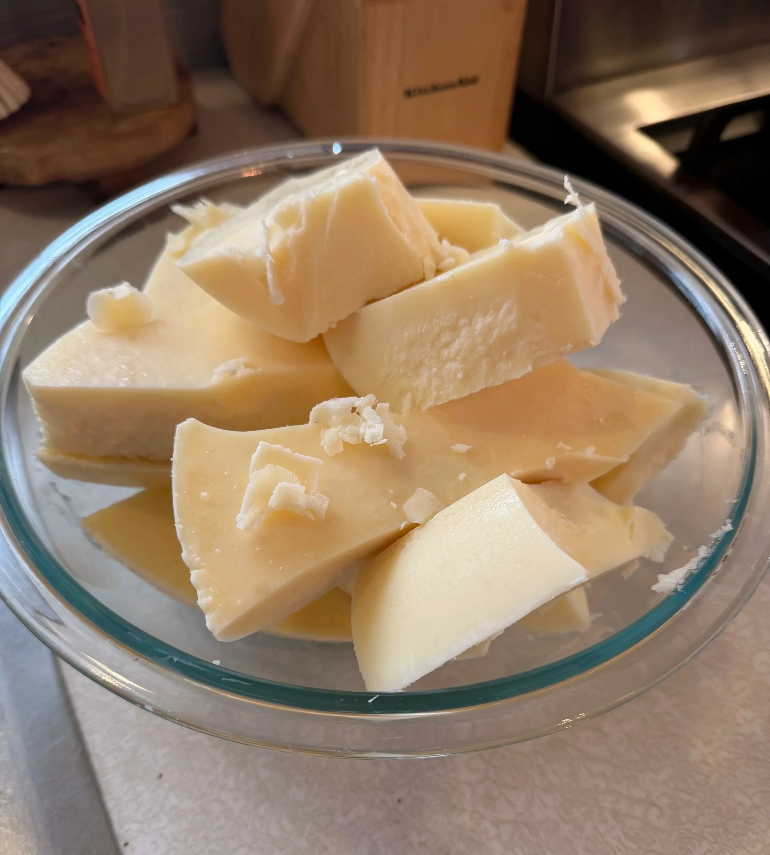 A glass bowl filled with white chocolate chunks on a kitchen counter.