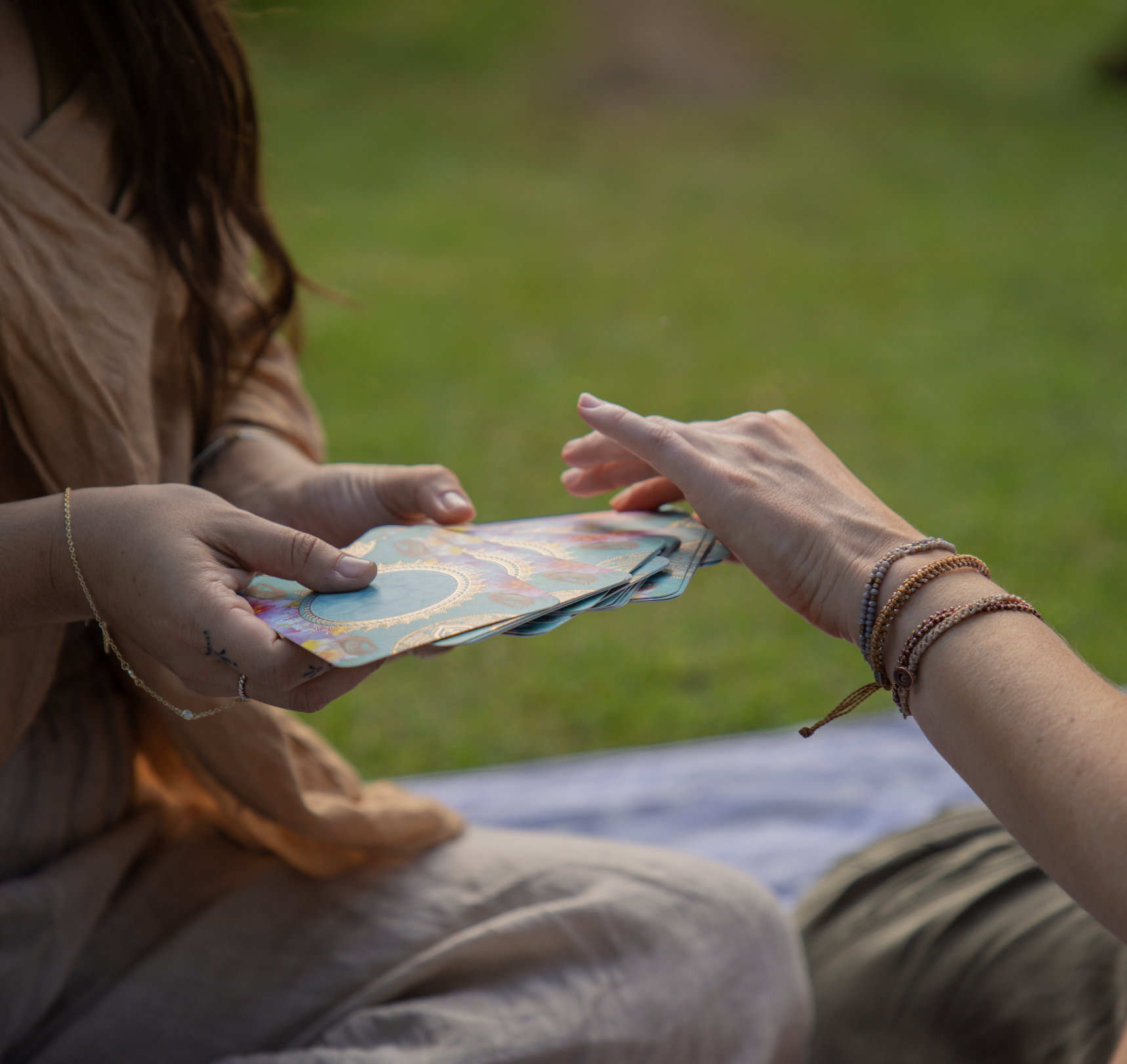 Two people exchanging a deck of tarot cards outdoors.