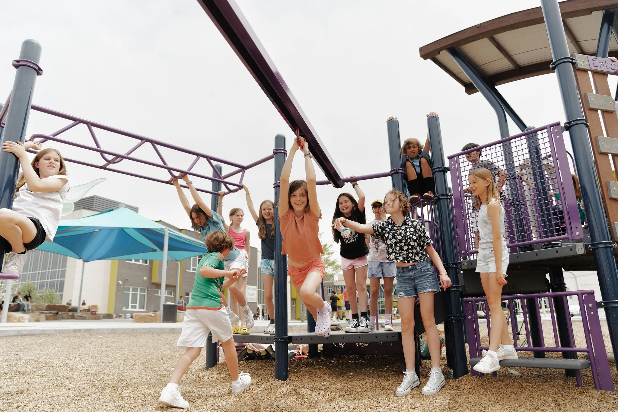 Children playing and swinging on a playground structure at a school or park.