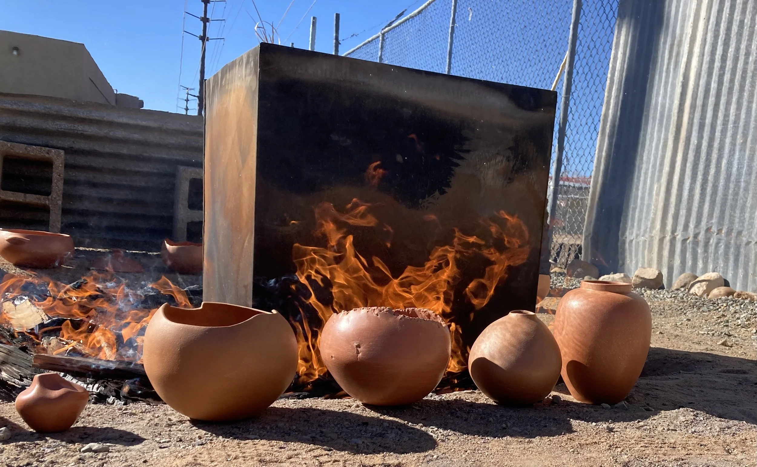 Clay pots in front of kiln ready for firing.