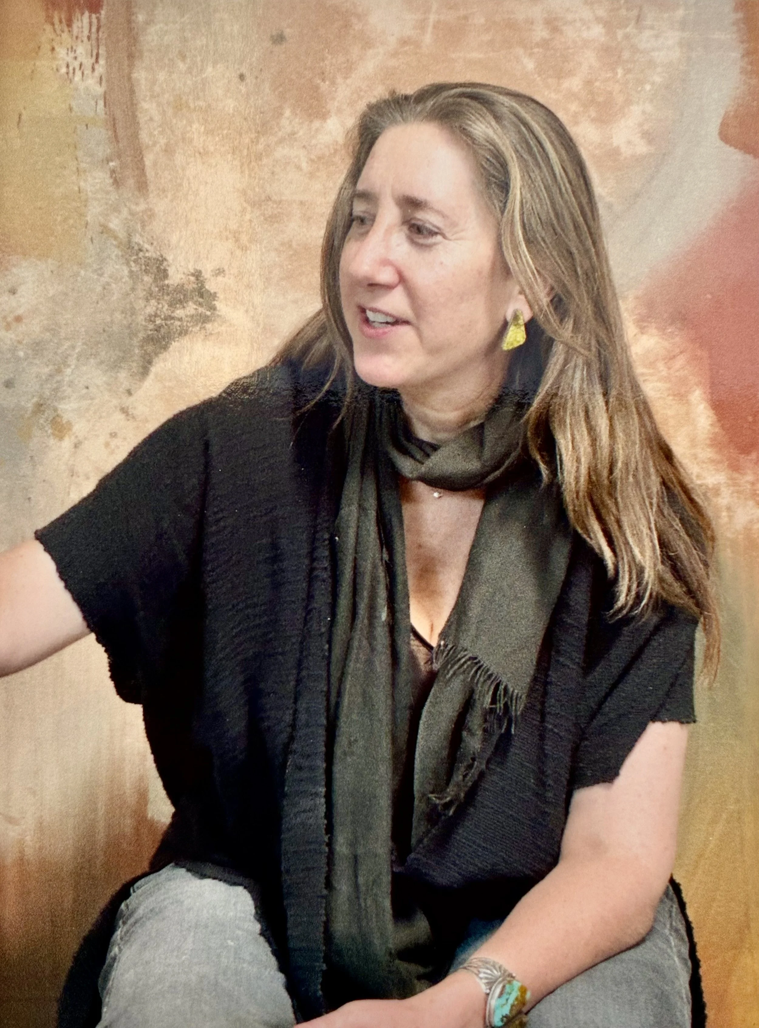 Portrait photo of Jenna Ritter seated in front of one of her natural paintings.