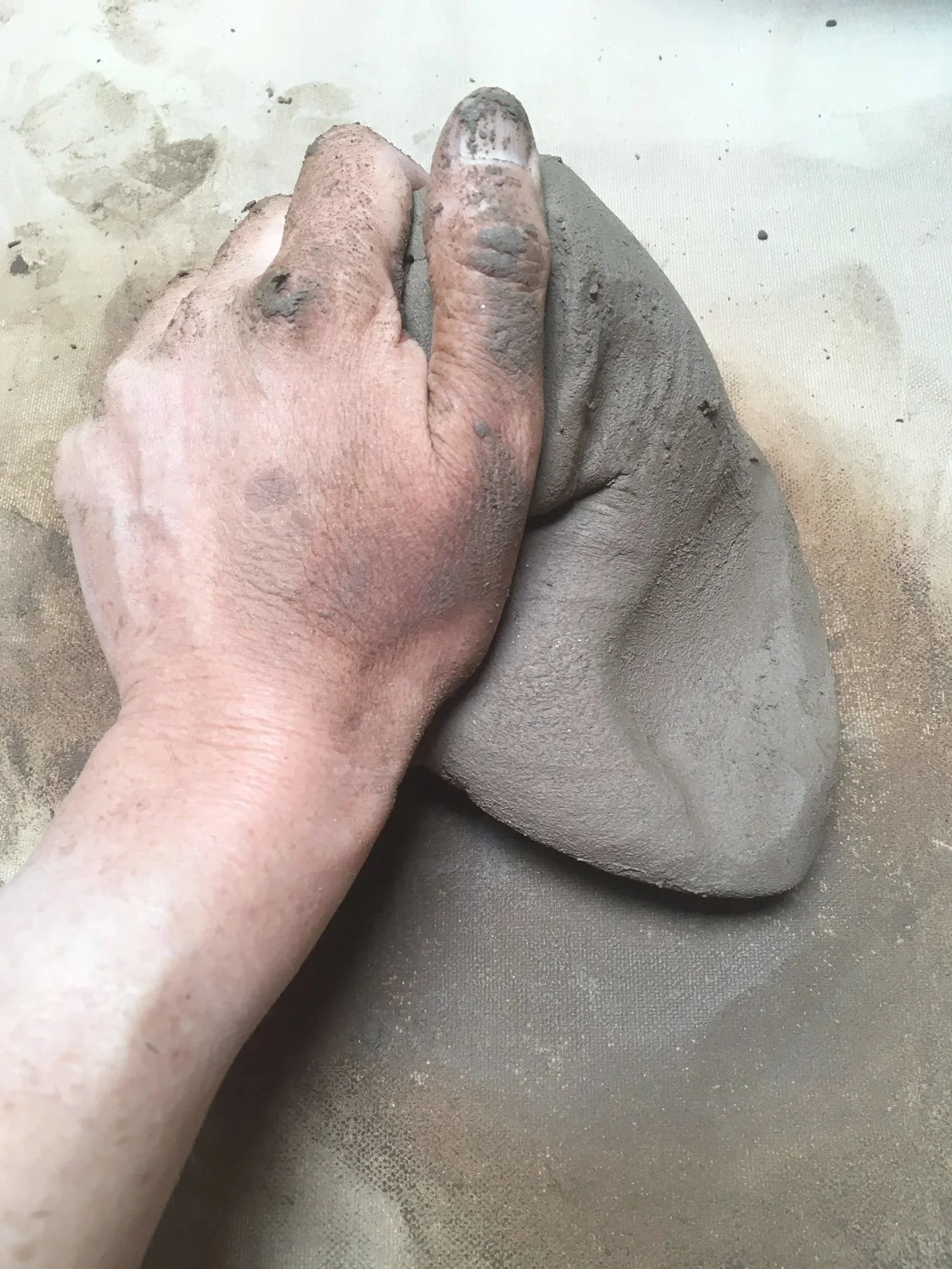 Jenna kneading clay with her hand.