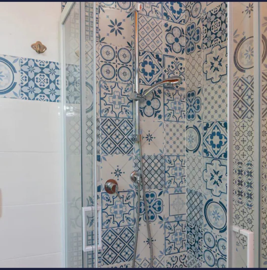 Incorpo doccia con rivestimento di piastrelle decorative blu e bianche e una minispalliera.