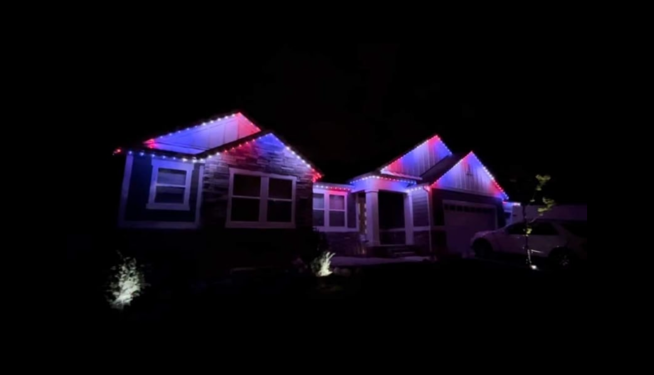 A house decorated with red, white, and blue Christmas lights at night.