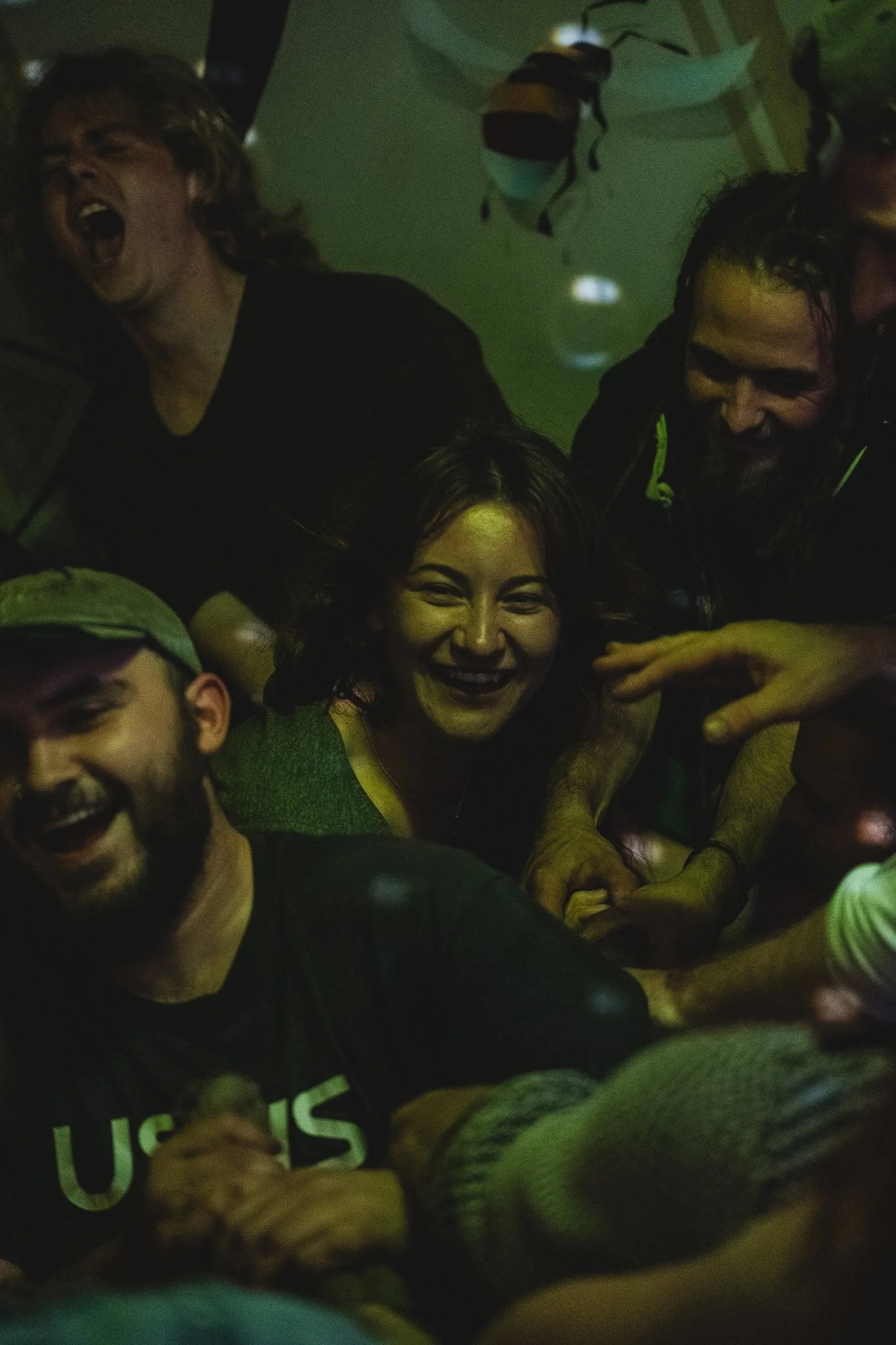 Group of people having fun and laughing together in a dark, lively setting.