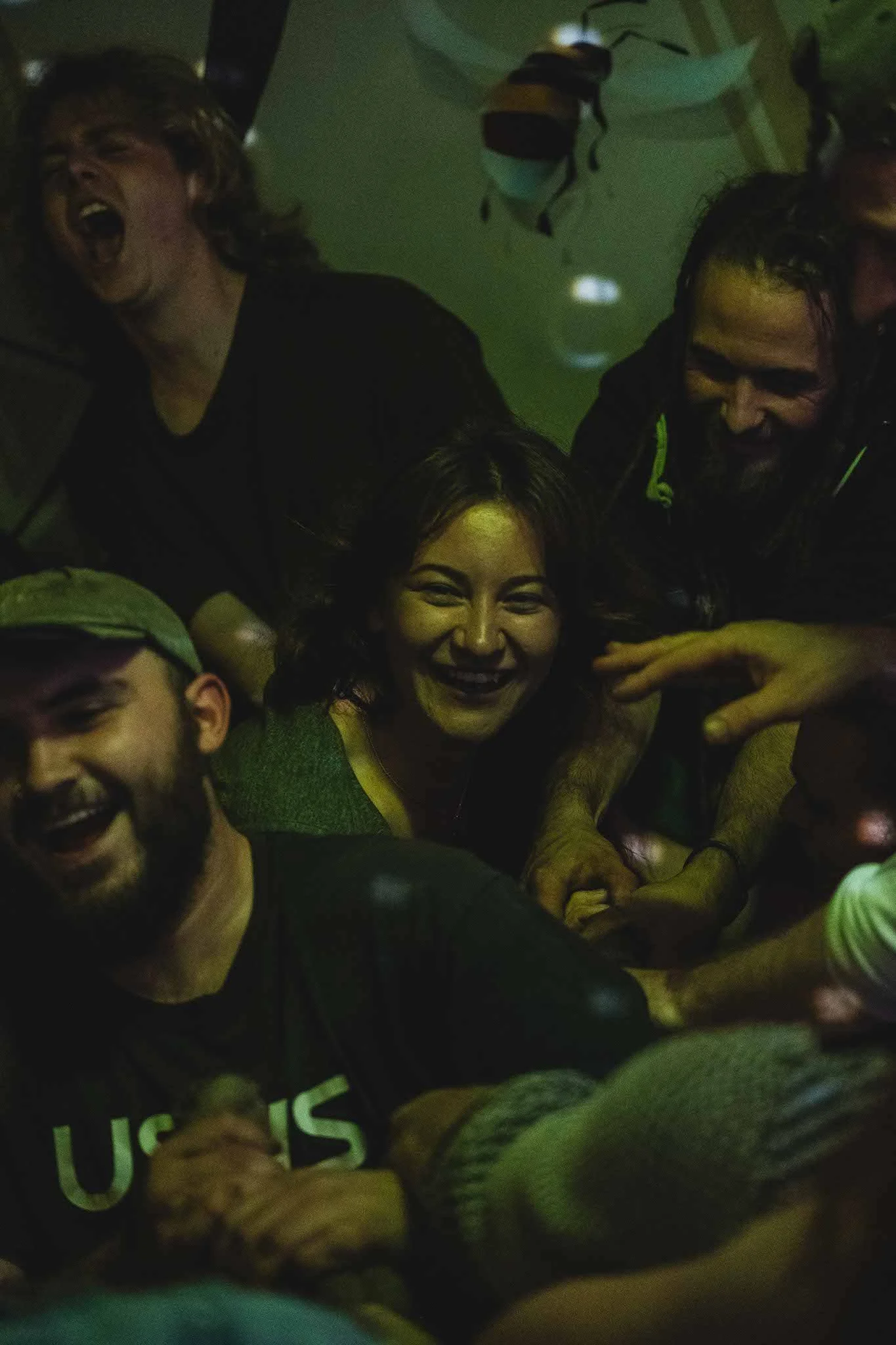 A group of people laughing and playing together in a dimly lit room.
