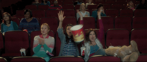 Group of women cheering in a cinema, representing shared joy and collective feminine experience.