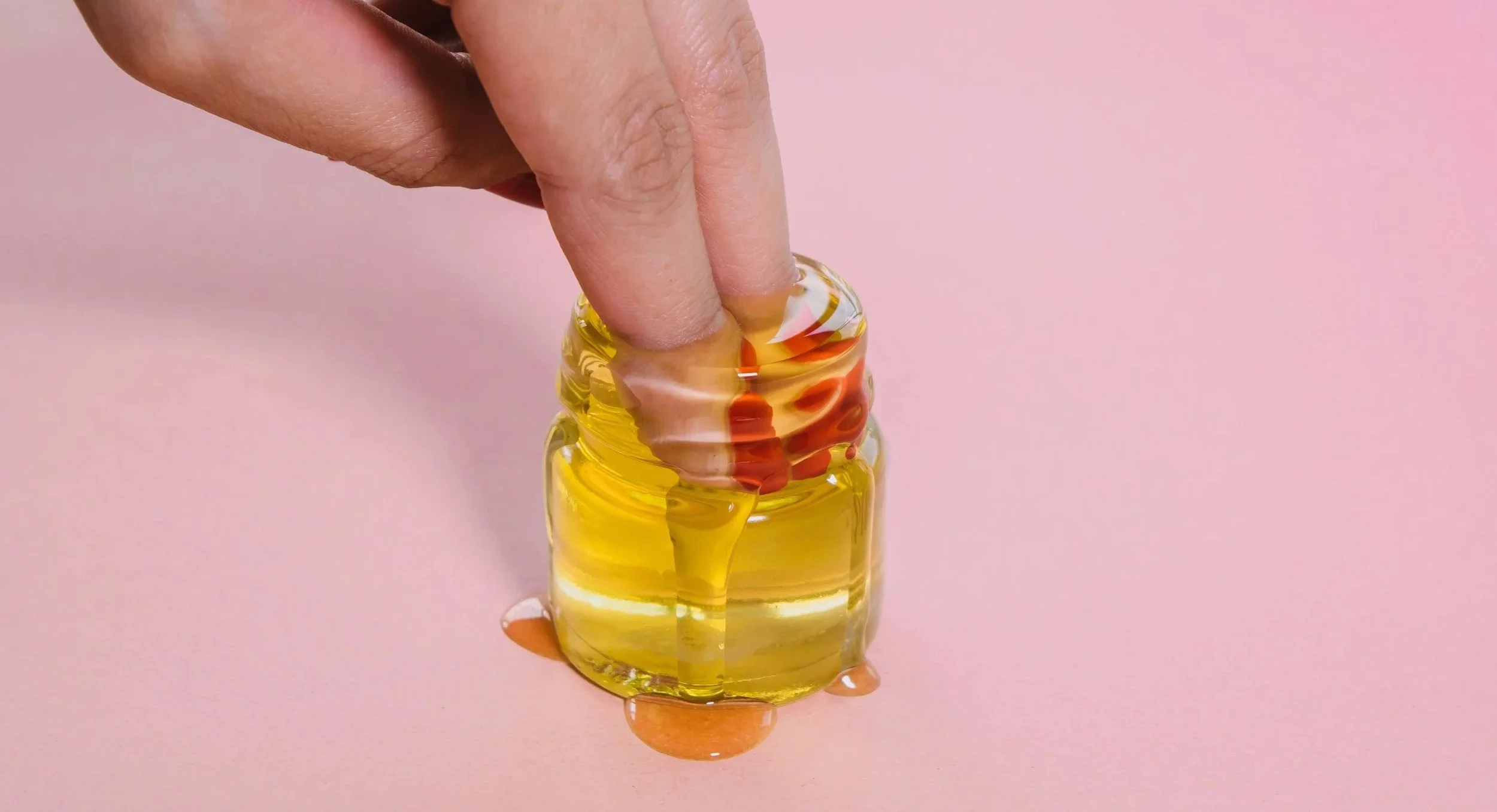 Fingers dipping into honey, representing lubrication, touch, and sensory preparation.