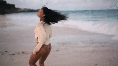 Woman dancing on a beach smiling, representing confidence, embodiment, and sensual self-connection.