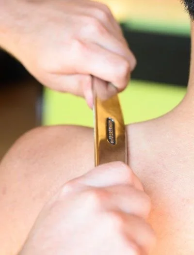 A person receiving a tattoo on their shoulder from an artist.