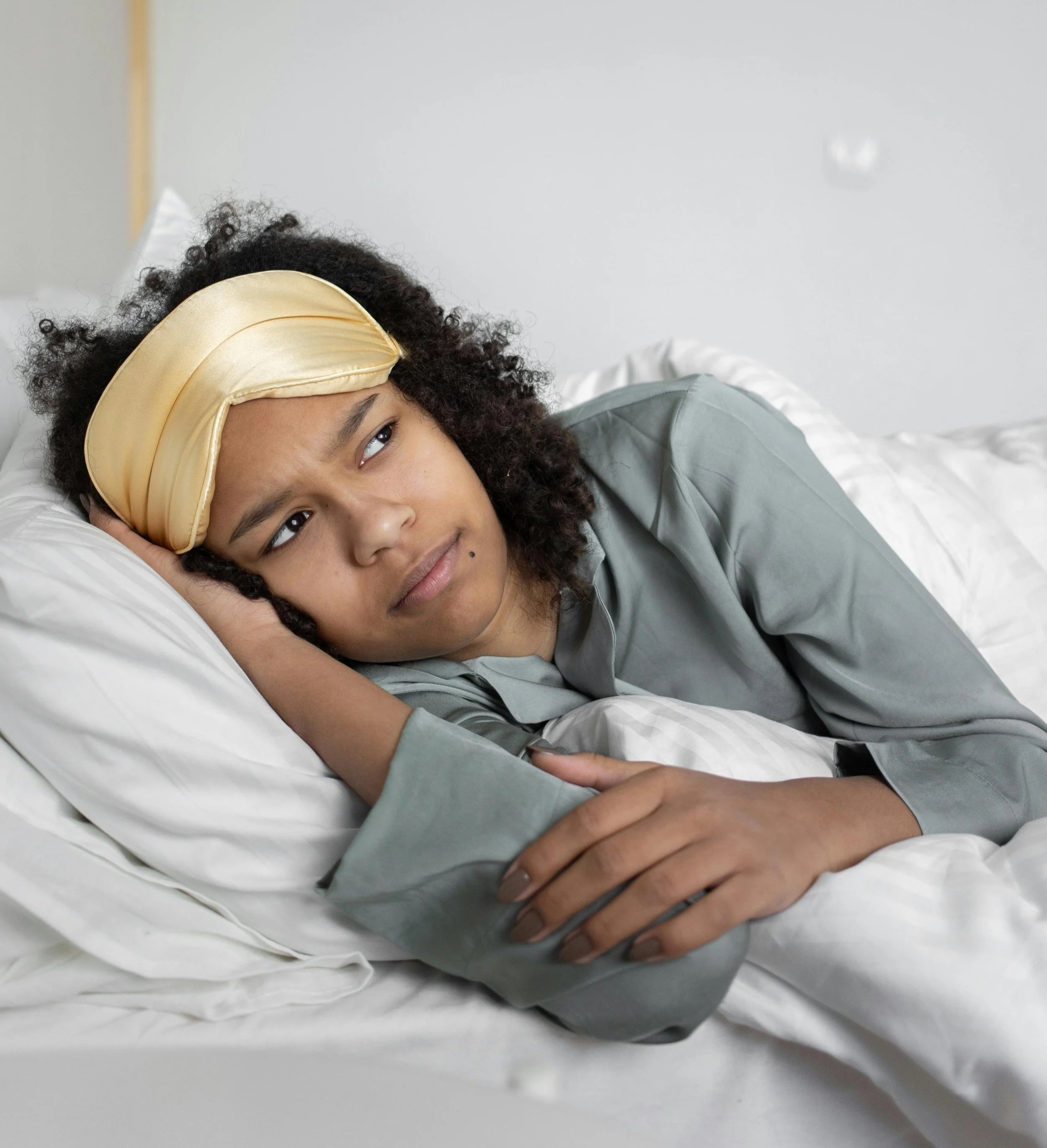 Woman lying awake at night with eye mask pushed up, representing high-functioning anxiety therapy in NYC