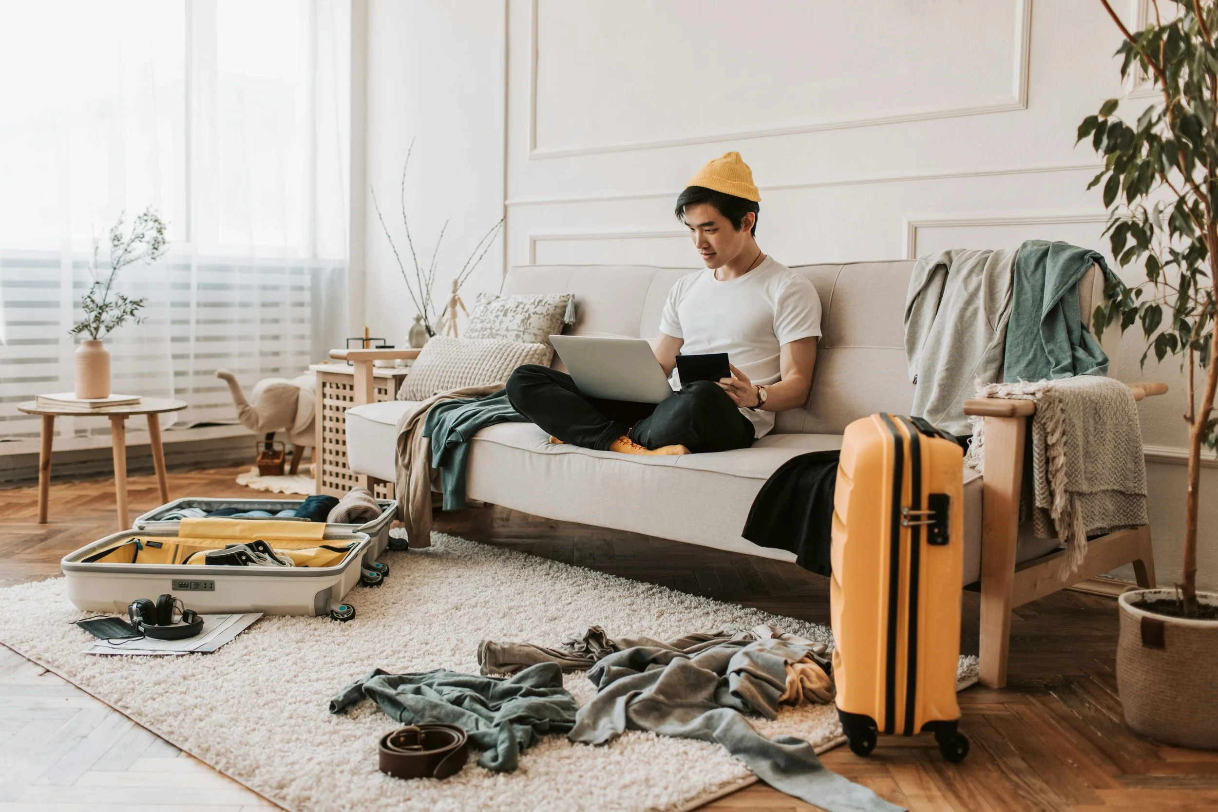 Man sitting on a couch with an open suitcase, representing uncertainty and change during a life transition.