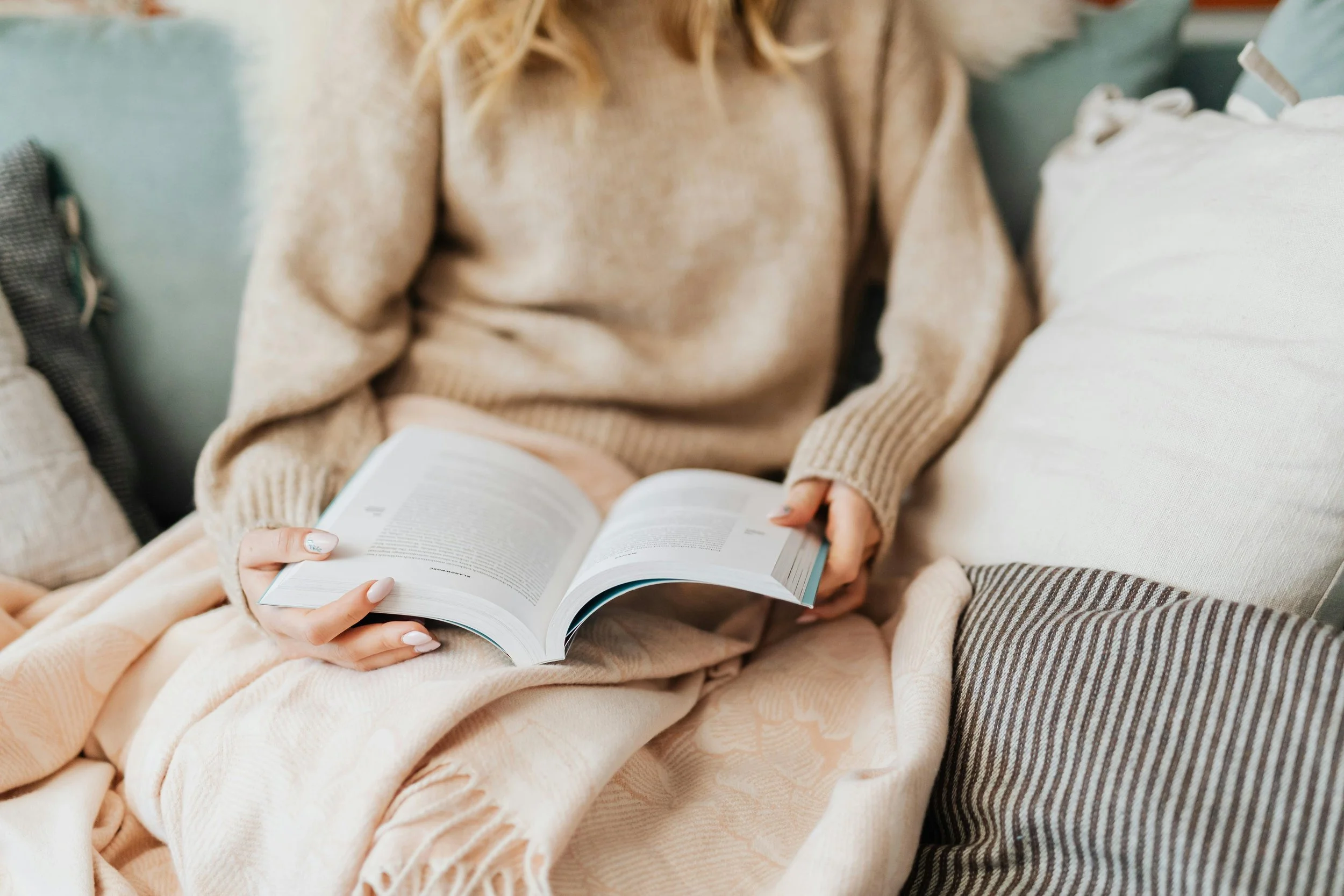 Person sitting on a couch reading, representing reflection and personal space in therapy