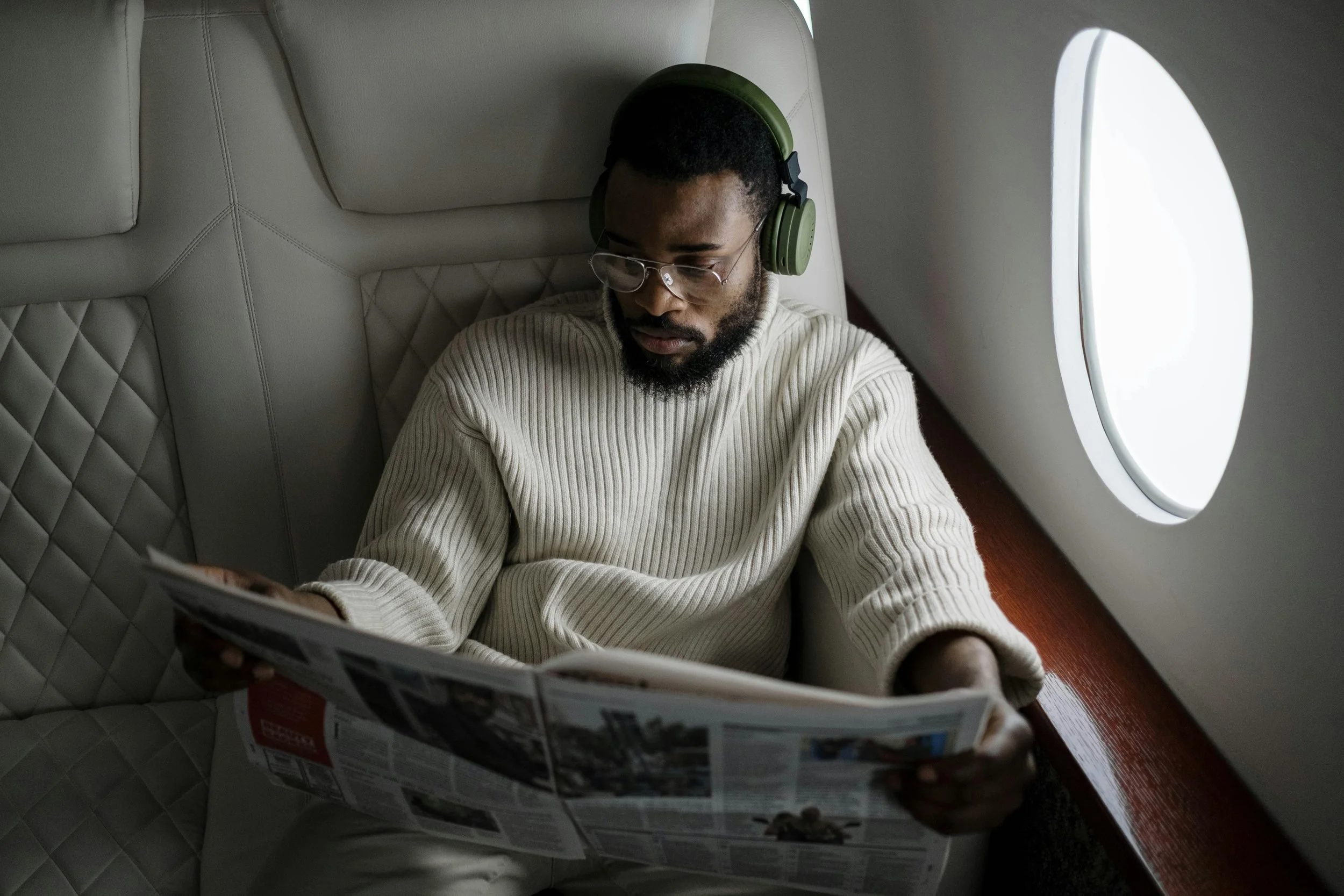 Man reading a newspaper on an airplane, representing navigating change and transition in life.