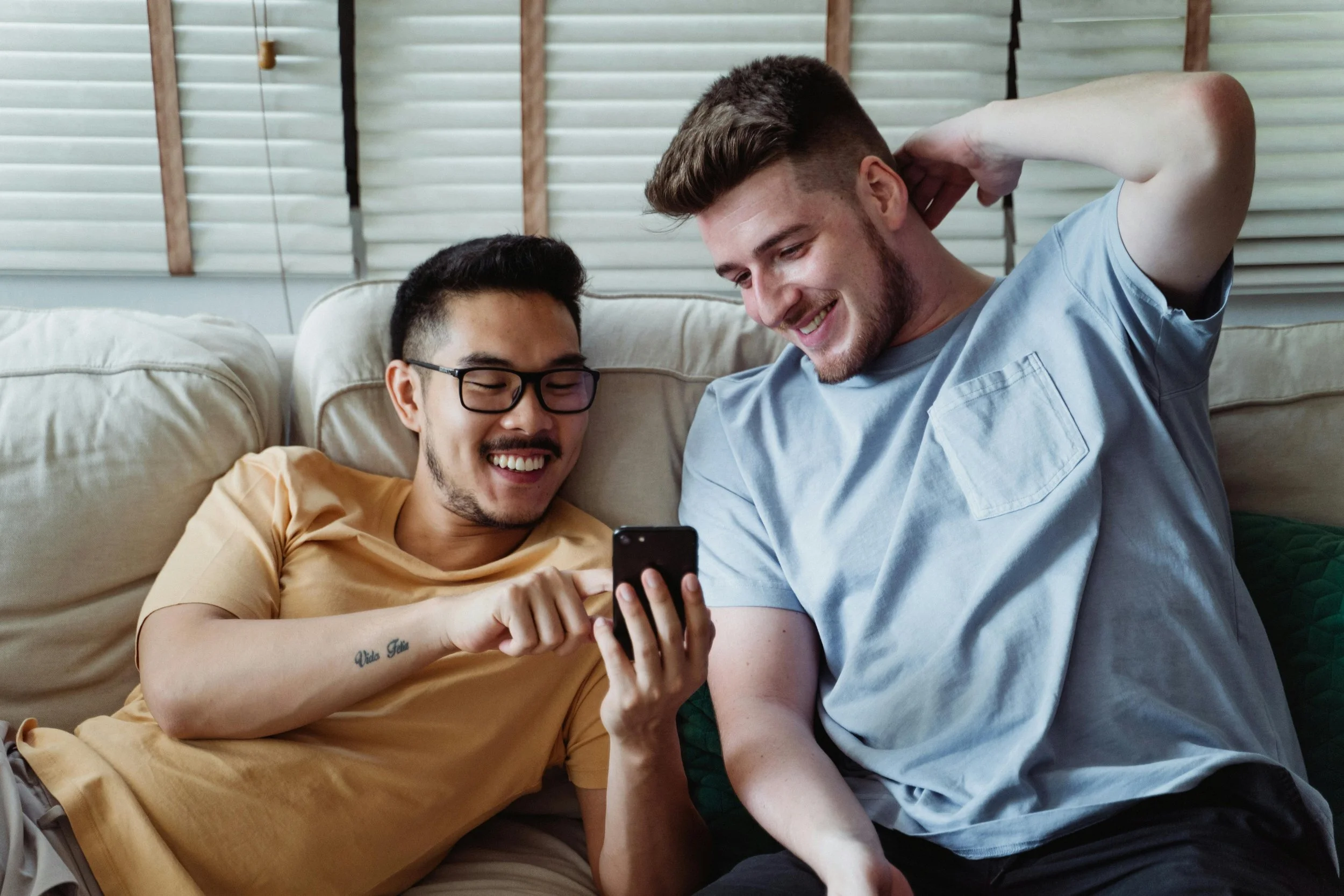 Two men sitting together on a couch, sharing a moment of connection and safety in trauma-informed therapy.