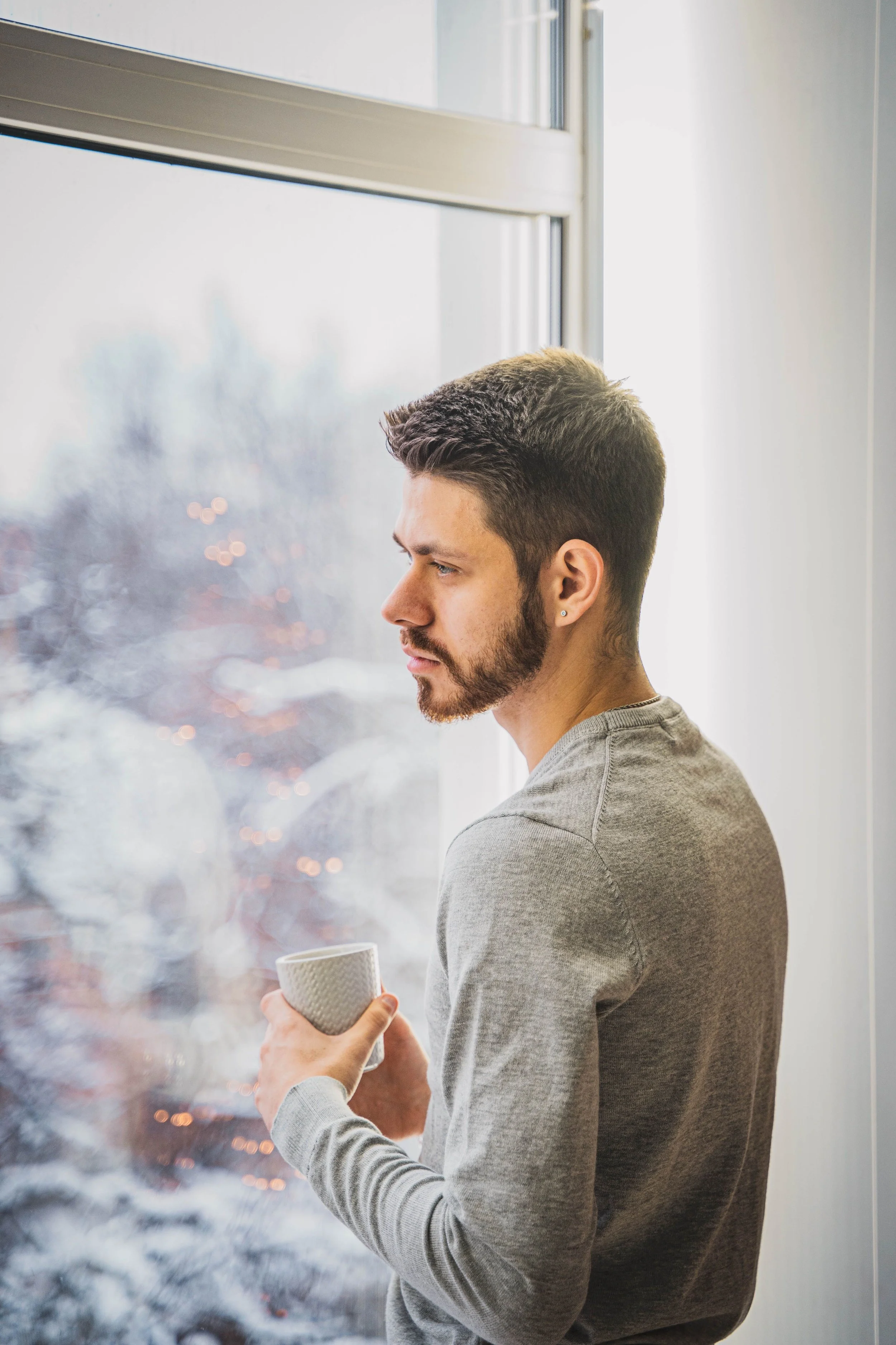 man looking out window representing high-achieving men therapy anxiety IFS New York