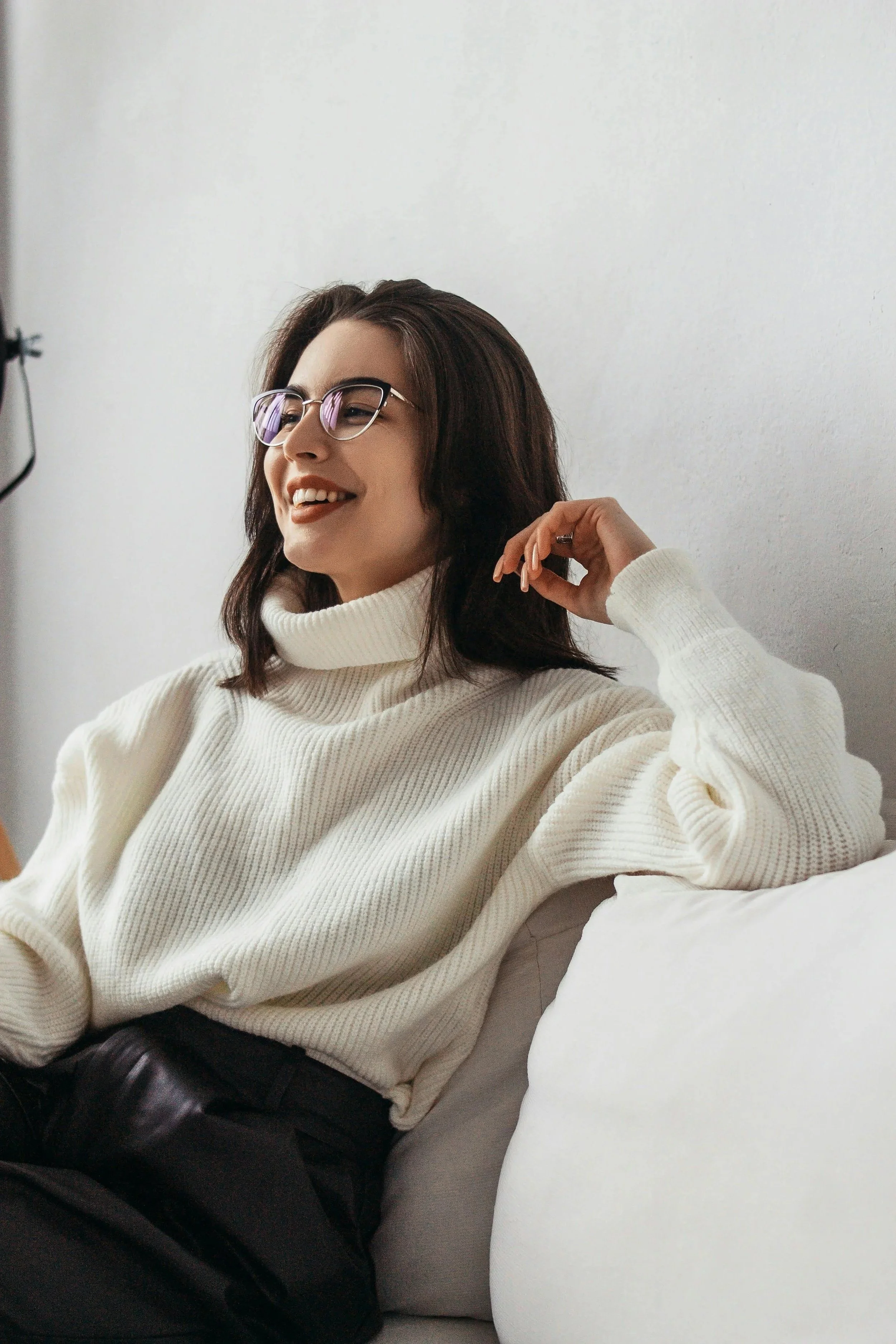 Woman sitting on a couch and smiling during a conversation, representing support and understanding in trauma therapy.