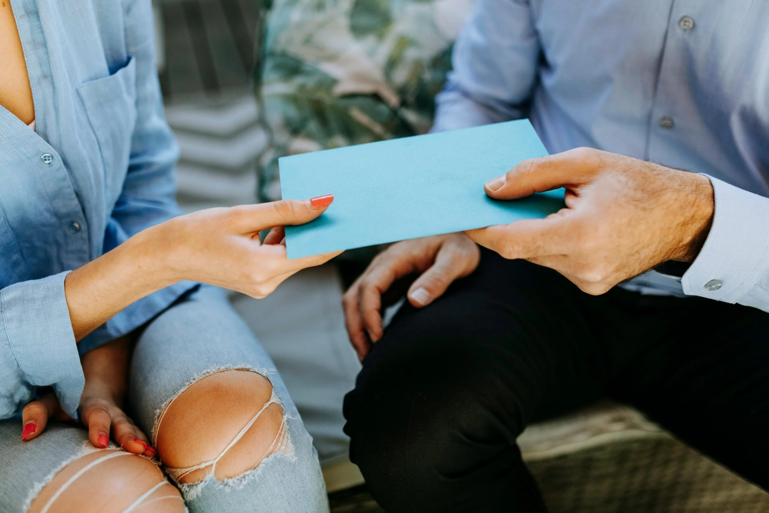 Two people exchanging an envelope, representing support, trust, and care in therapy