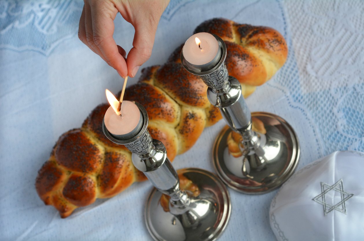 hands lighting Shabbat candle with challah representing Jewish therapy for anxiety New York City