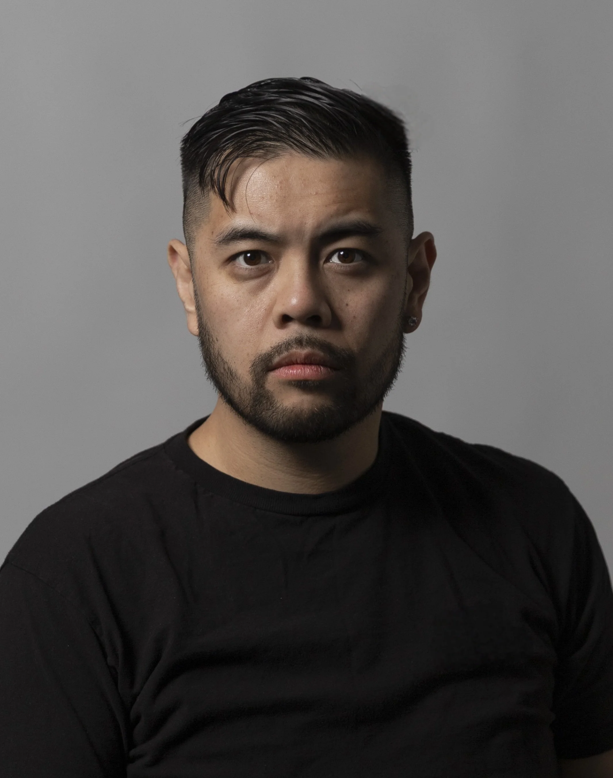 Portrait of Ryan Ventura with short dark hair, beard, wearing a black shirt, against a plain grey background.