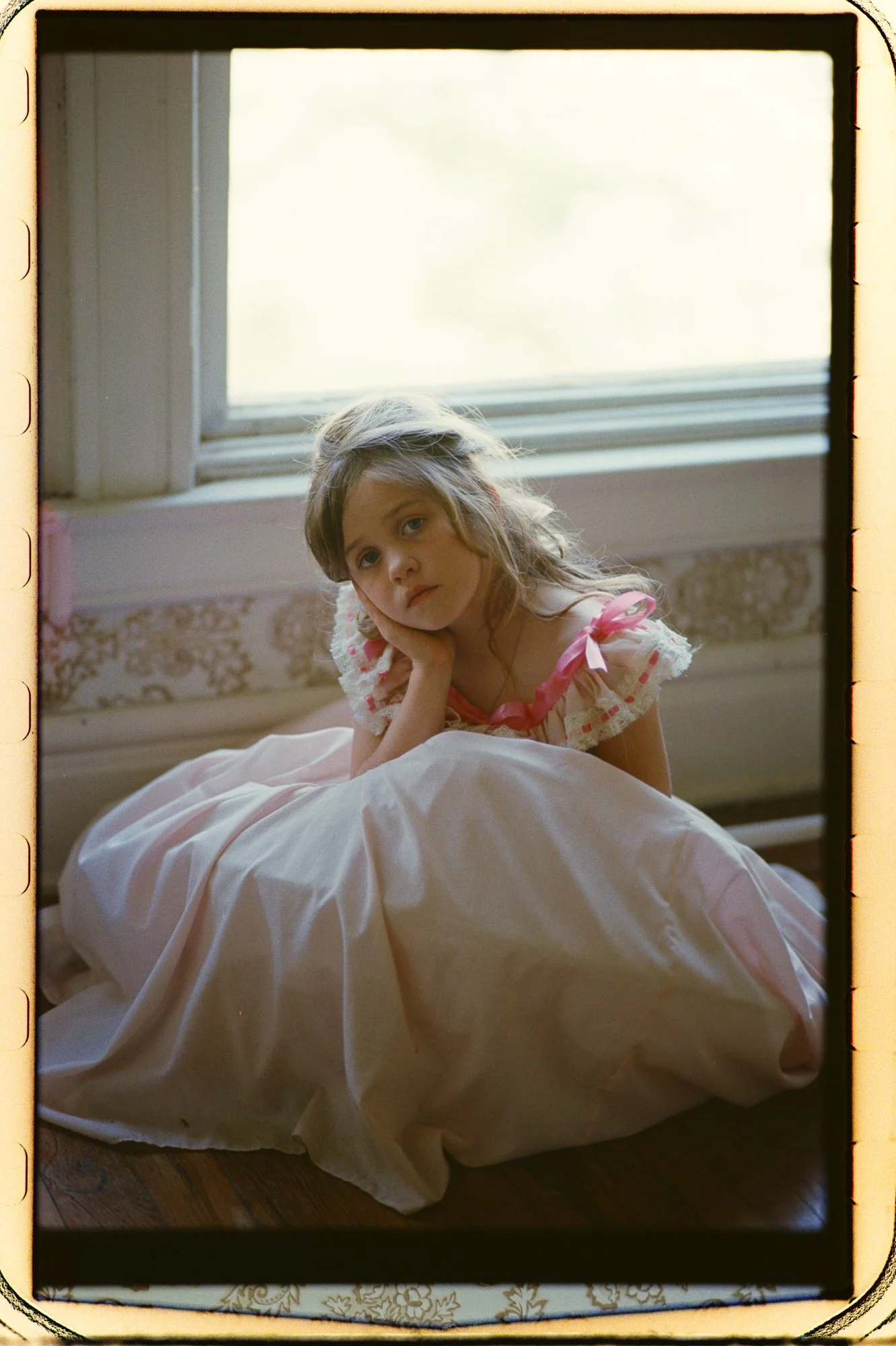 Little girl in a pink dress sitting looking at camera