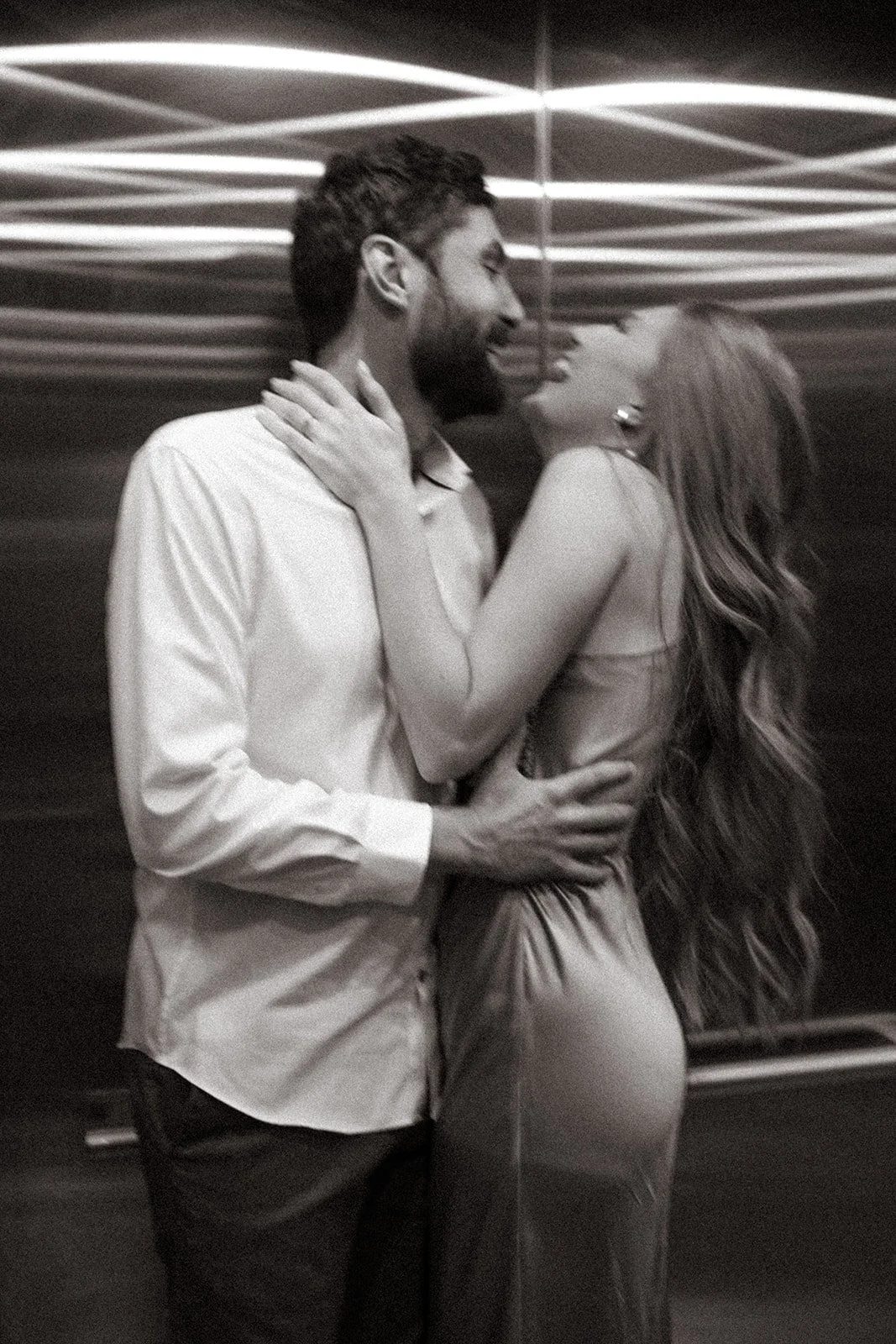 Husband and wife embrace in laughter in a candid black and white photo