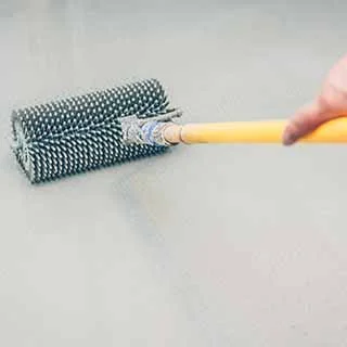 A person using a textured wallpaper steamer on a wall