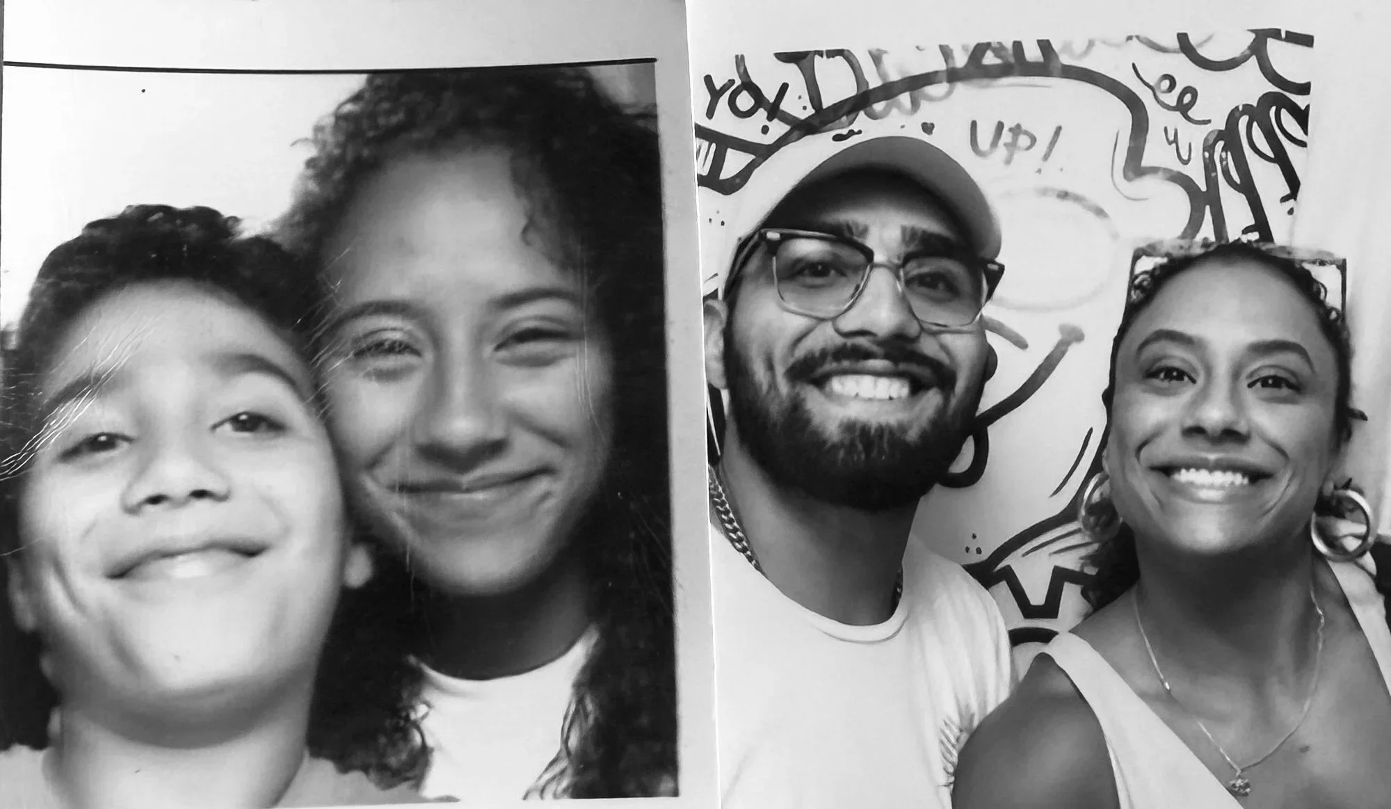 Black and white photo of two women smiling, one with curly hair and the other with straight hair, in a close-up, studio portrait.