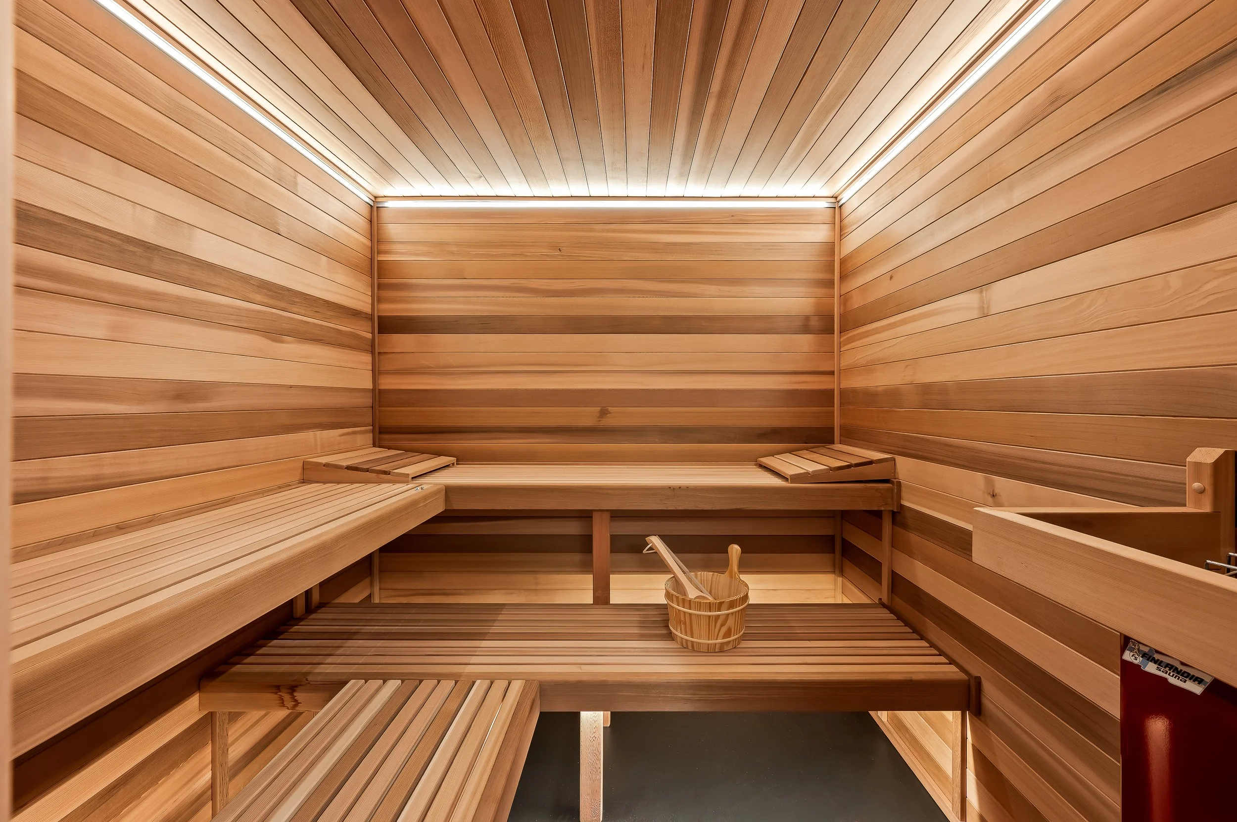 Interior of a wooden sauna with benches and a bucket with a ladle.