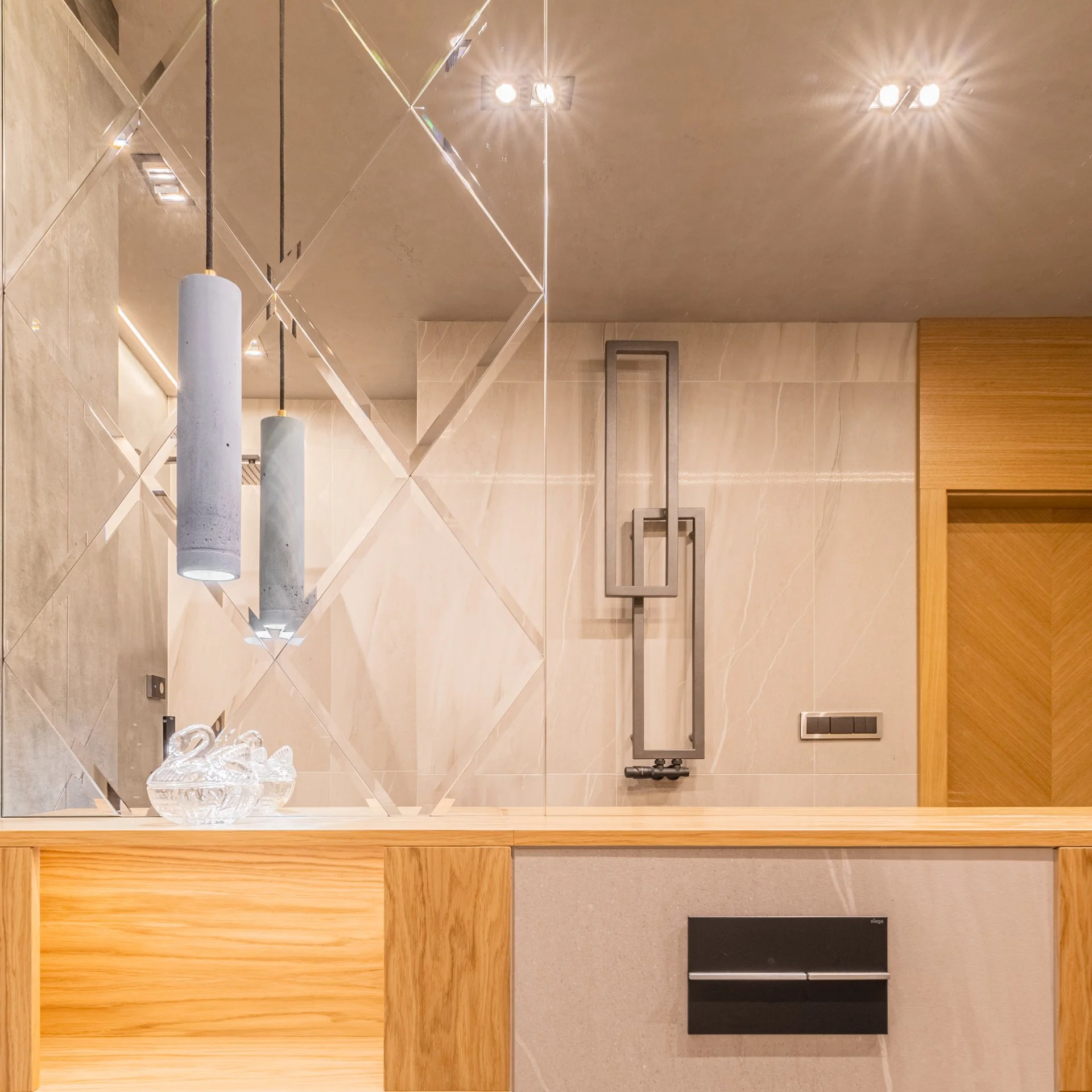 Modern interior with a large tiled mirror, pendant lights, a wall-mounted sculpture, and a wooden and stone counter.