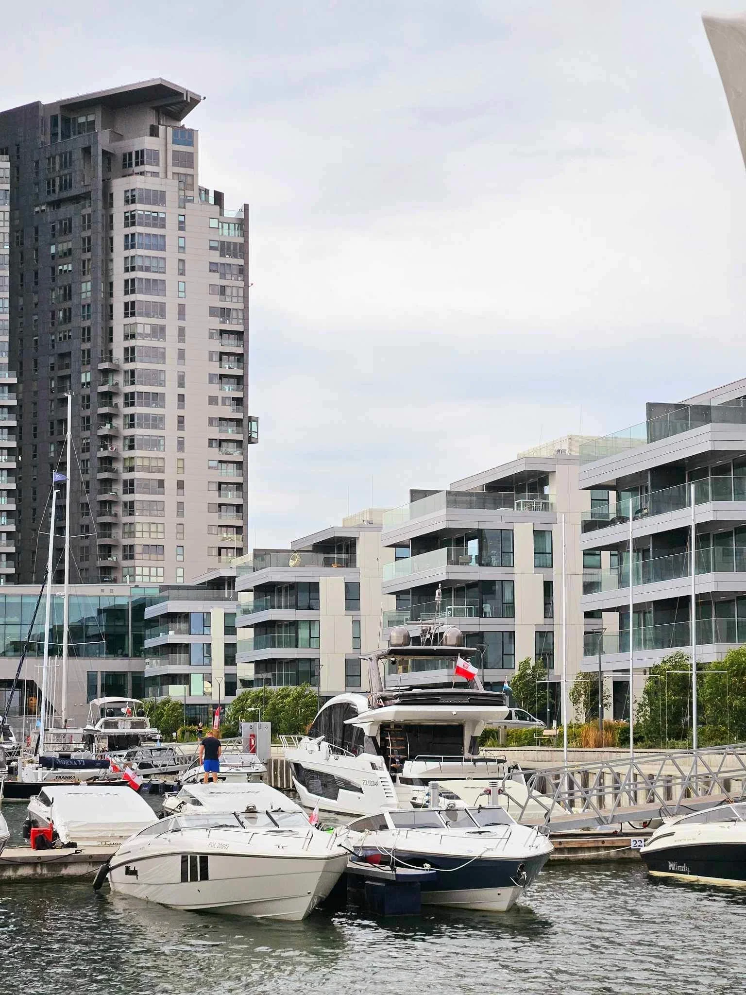 Boats docked at a marina with modern buildings in the background