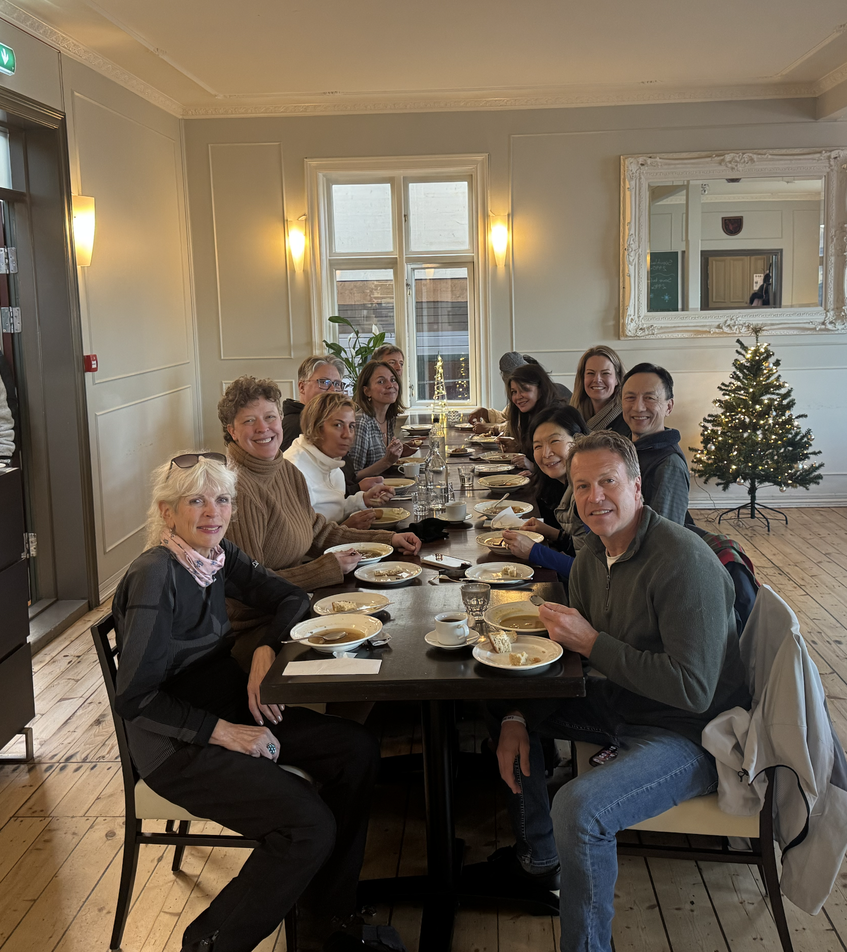 A group of people within retreat planning for facilitators sit around a dining table eating a meal in a warmly lit room