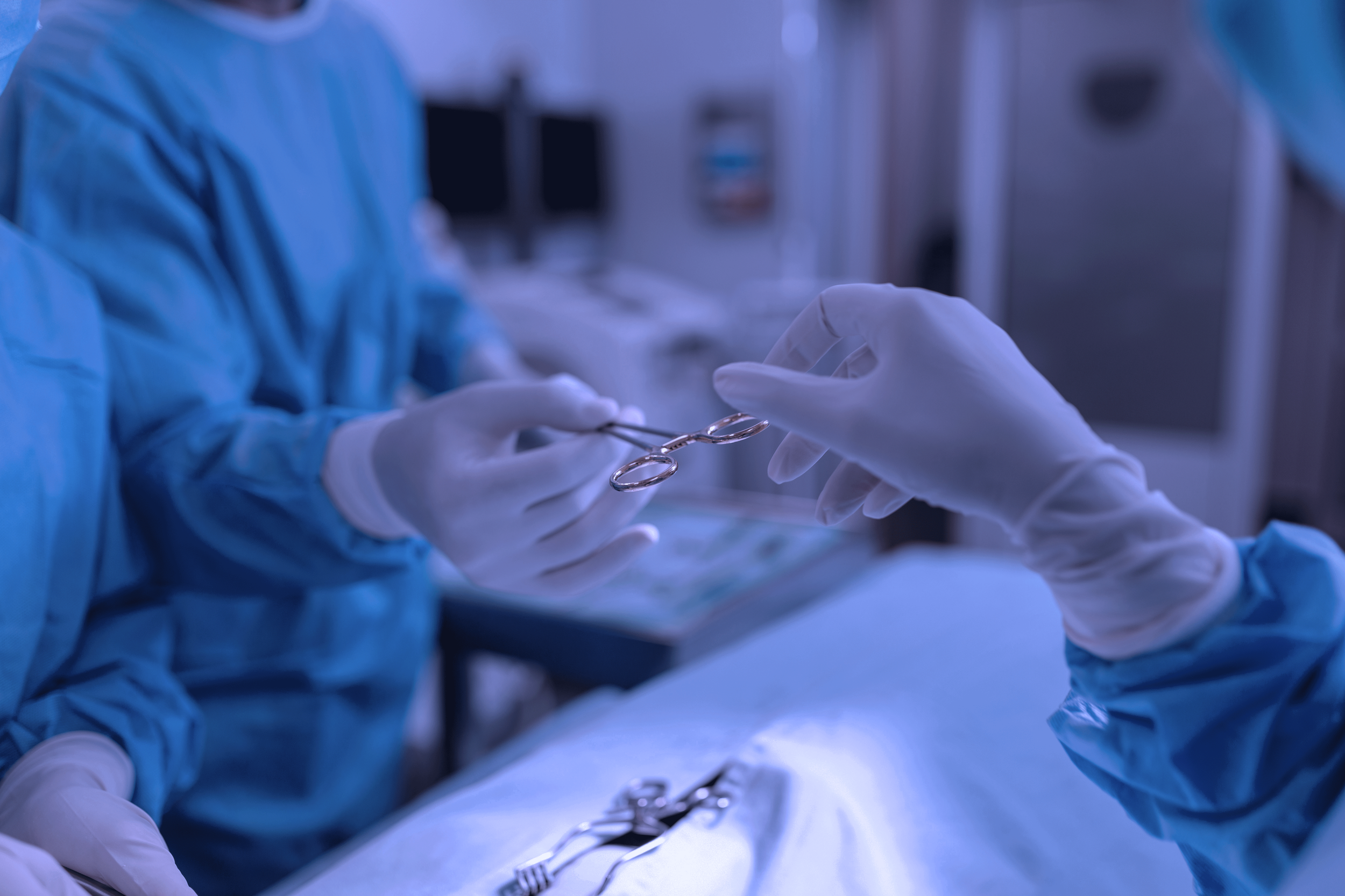 Two surgeons handing over a surgical scissors in an operating room.
