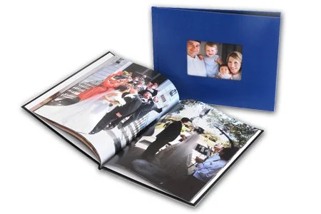 Open photo album with family pictures next to a closed blue photo album with a family picture on the cover.