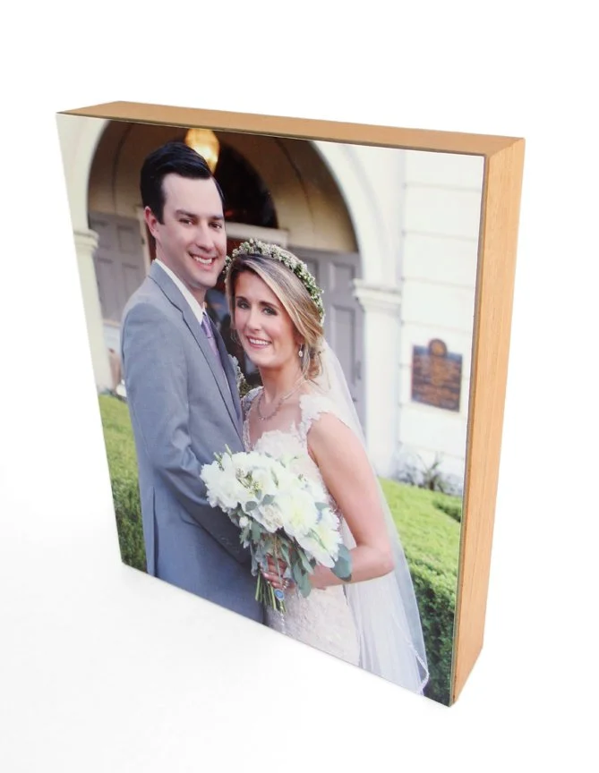 Framed portrait of a newlywed couple in wedding attire standing outdoors in front of a building.