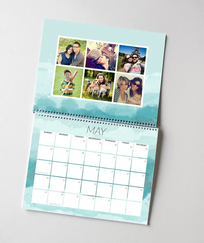 A desk calendar open to May with six personal photos on the top page, showing various people and pets outdoors and at landmarks, and a traditional calendar grid below.