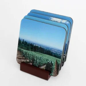 A set of four landscape photographs of fields and trees on display in a brown stand.