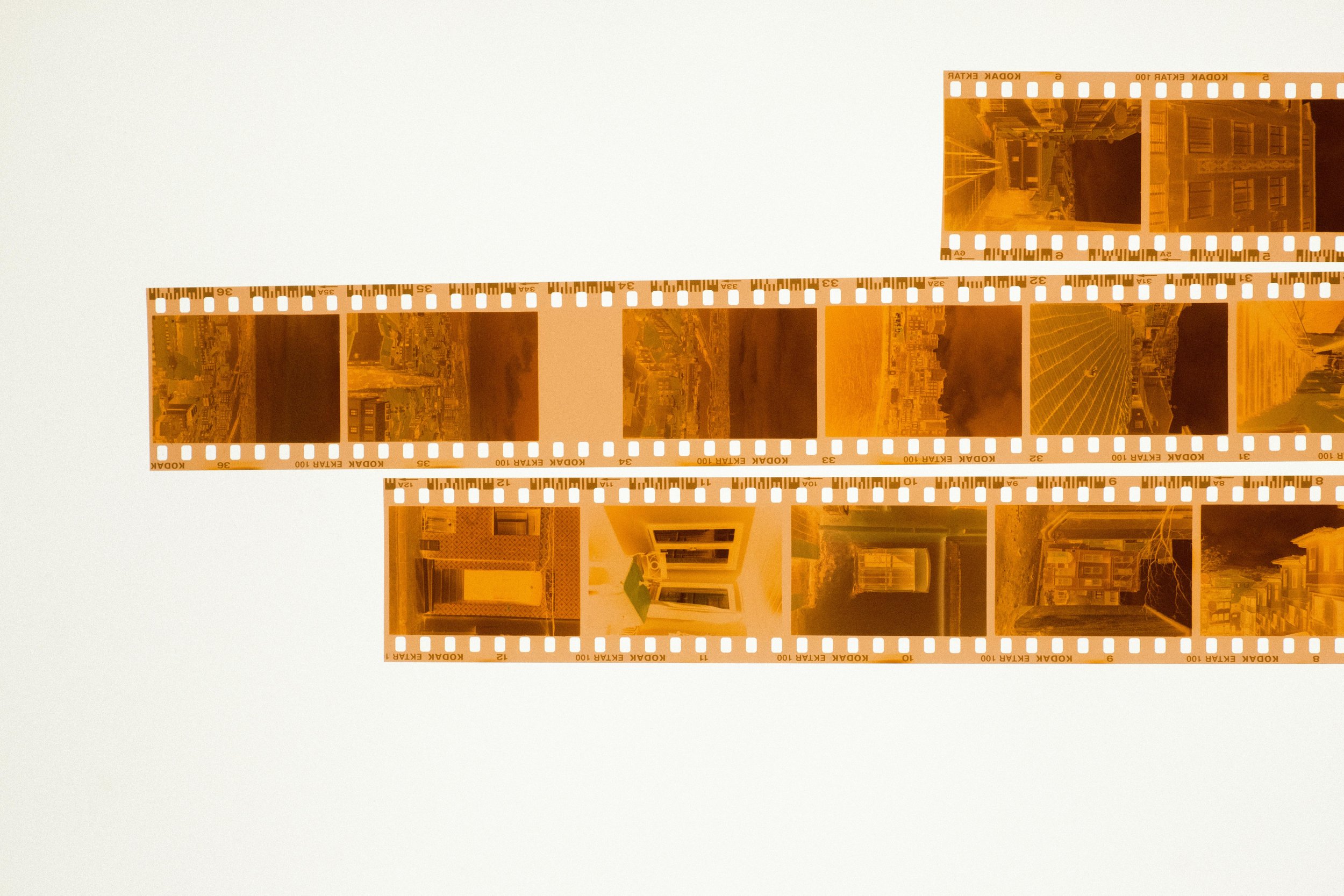 Color negative film strip with multiple photos showing buildings, streets, and cityscapes, placed on a white background.