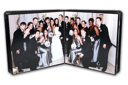 A wedding photo displayed inside a foldable photo frame, featuring a bride and groom surrounded by friends and family dressed in formal attire.